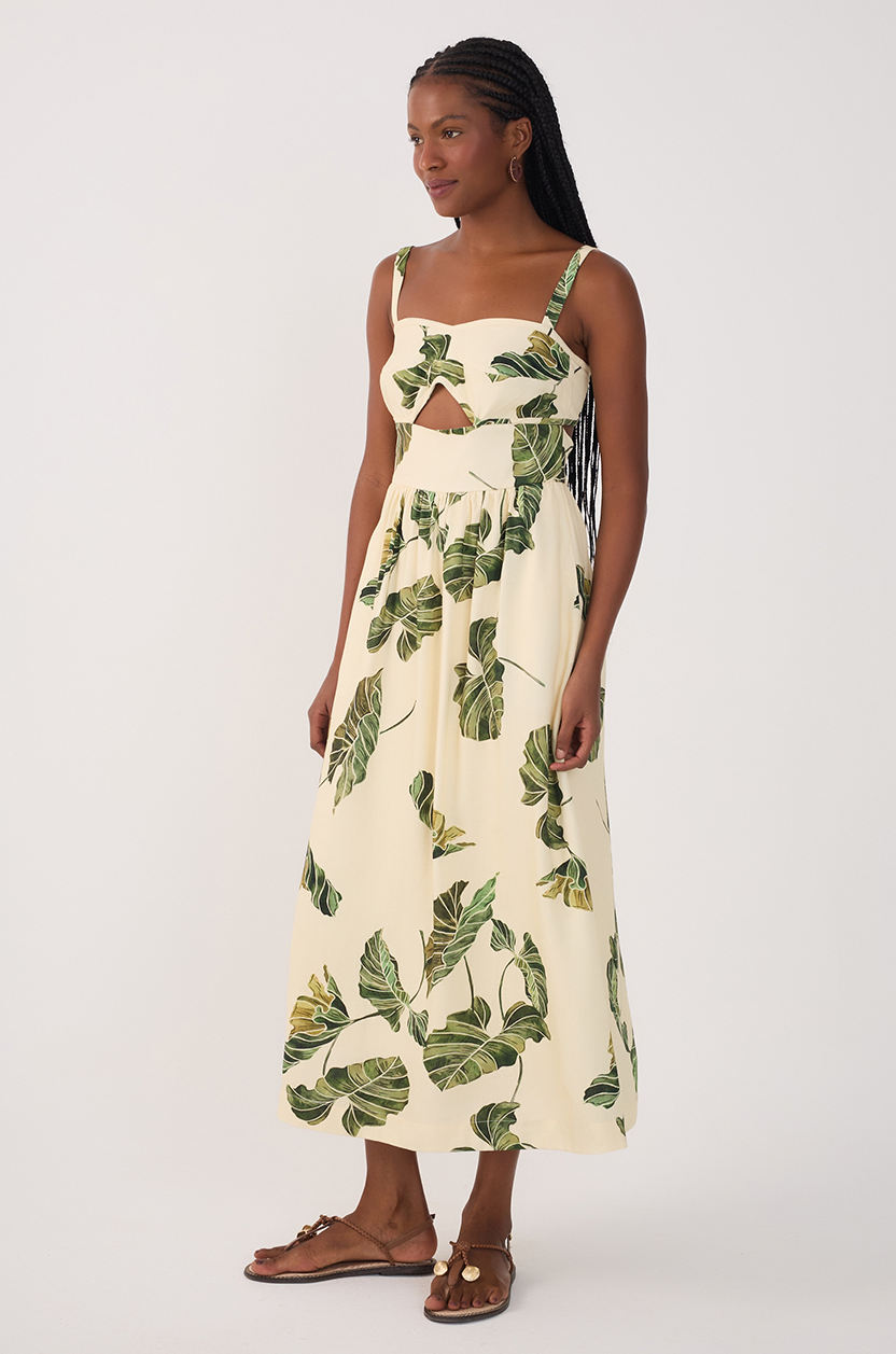 A woman in a Dress To Leaf Print Midi Dress and brown sandals, with long braided hair, stands against a plain white background.
