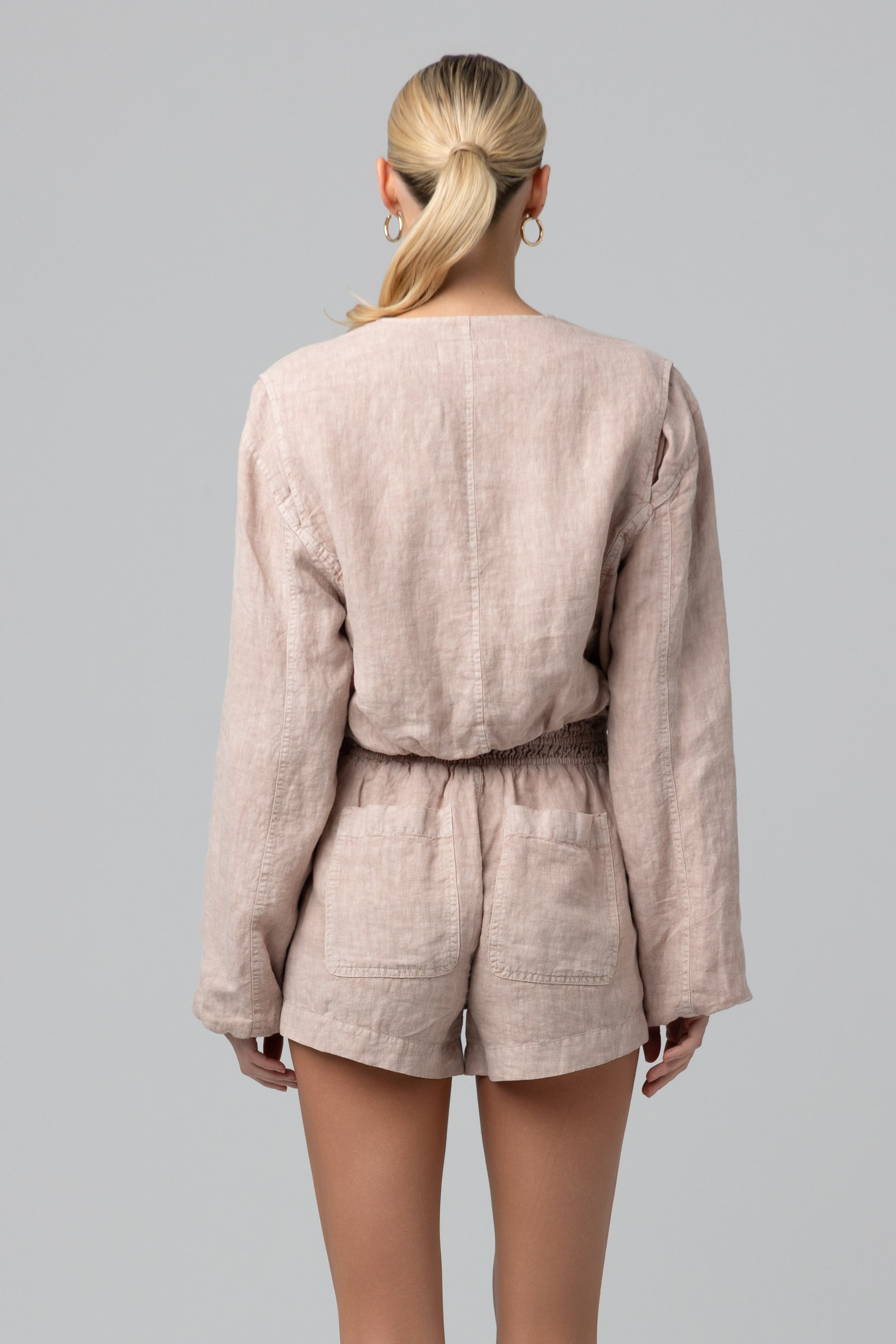 A woman with blonde hair in a low ponytail is shown from the back, wearing the Blank Read My Lips Jacket, against a plain gray background.