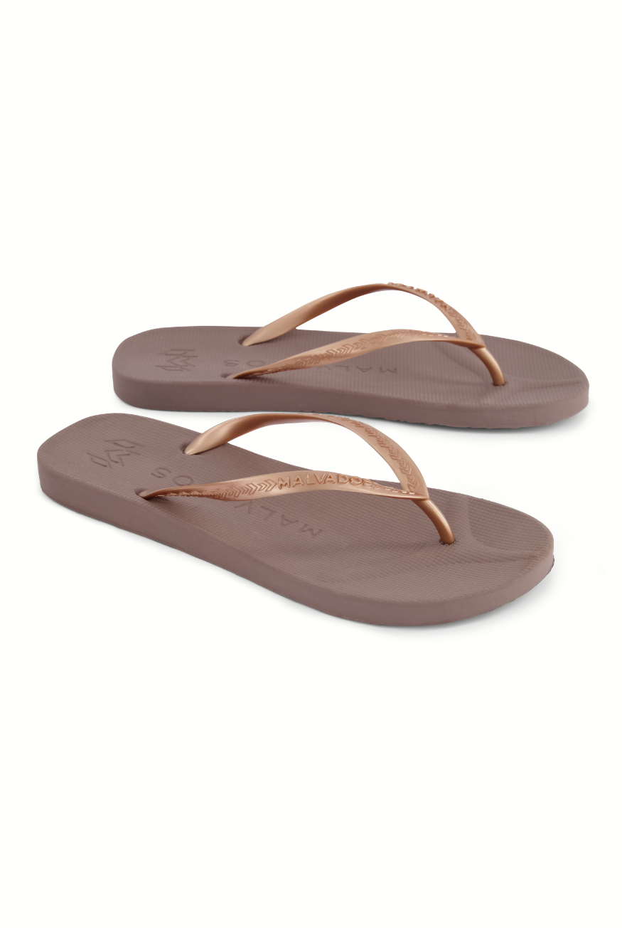 The South Moon Under Playa-malt sandals feature brown flip-flops with textured soles for enhanced traction and thin, slightly shiny straps, shown against a white background.