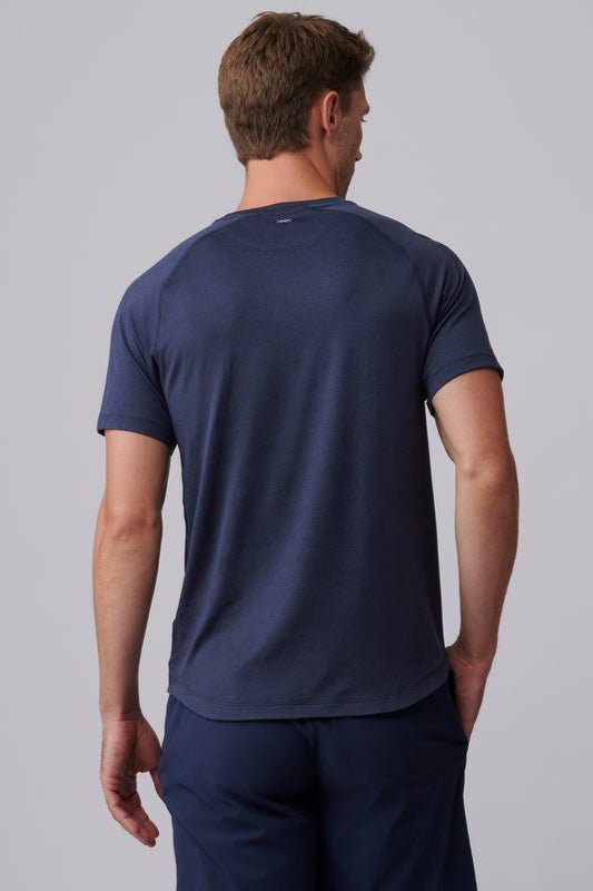 A man with short brown hair stands with his back to the camera, wearing a South Moon Under Atmosphere Tee in dark blue and matching shorts against a plain light gray background.