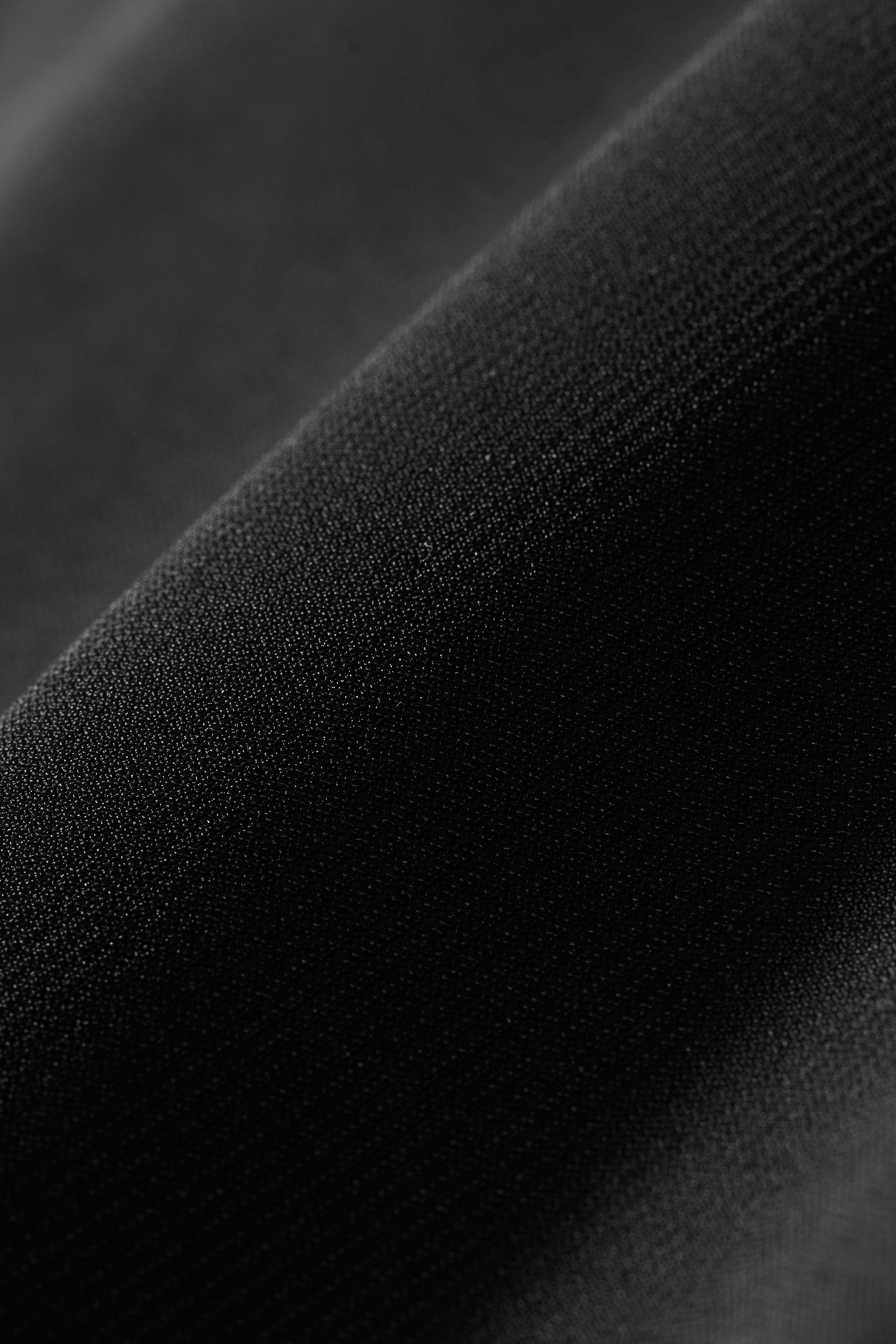 Close-up of South Moon Under’s Pursuit Pant fabric: smooth, black material with a fine weave, gentle folds, and soft lighting that highlights its lightweight durability and all-way stretch.