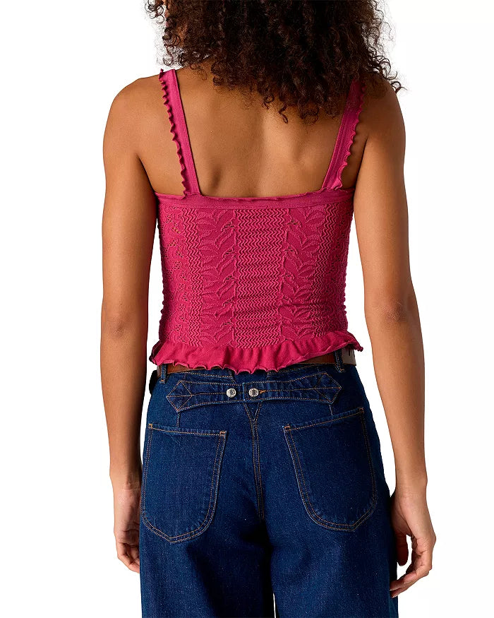 A person with curly hair is seen from the back, wearing Free People's So Soft Femme Square Top in magenta and dark blue high-waisted jeans.
