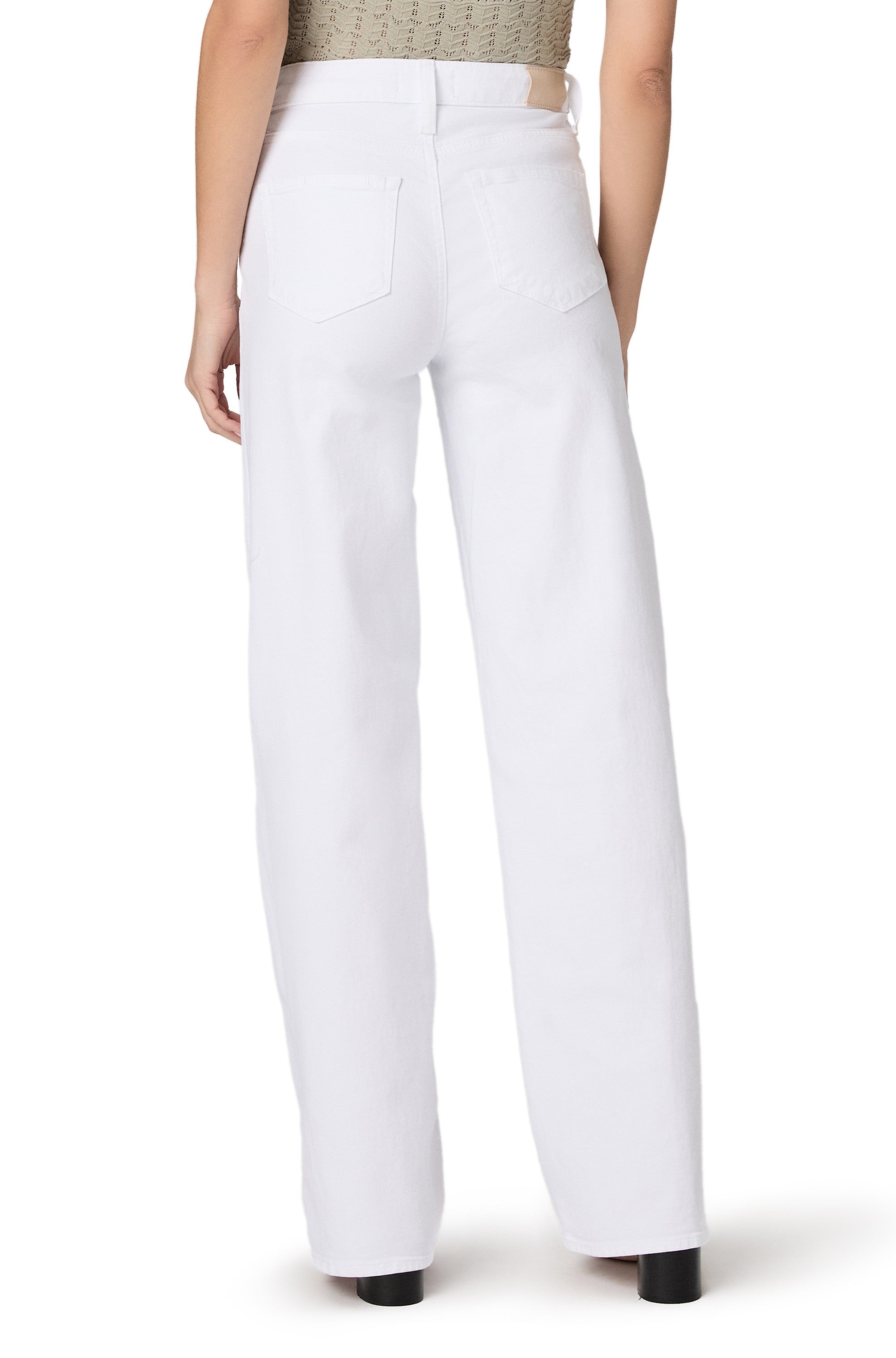 A person is shown from the back, standing against a plain white background, wearing Paige's Tatum 32 In Crisp White high-waisted, relaxed fit wide-leg jeans and a beige top.