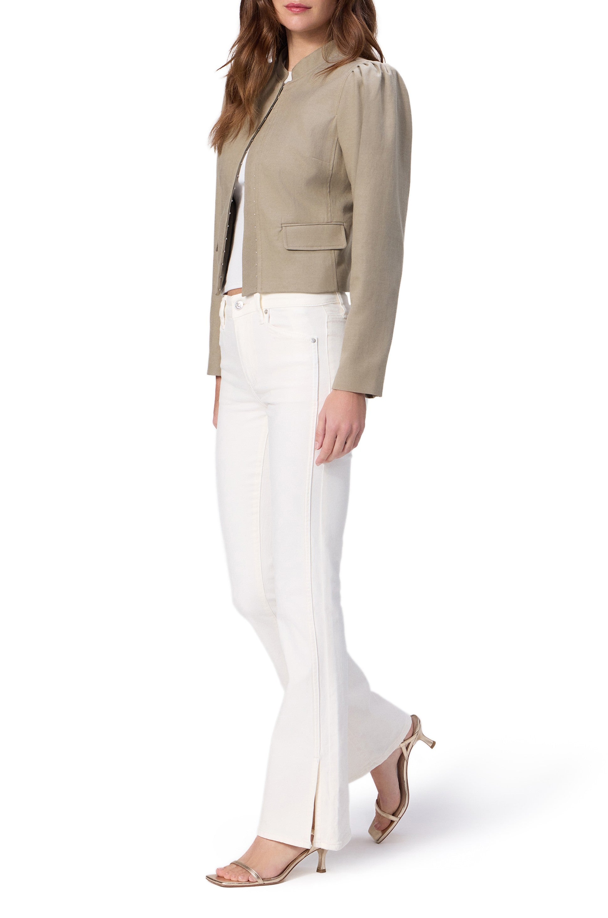 A woman wears the Paige Laurel Canyon 32" W/ Forward Panel + Vent ecru high-waisted bootcut jeans with front seams and side zippers, paired with a tan fitted blazer and nude heeled sandals, standing against a white background.