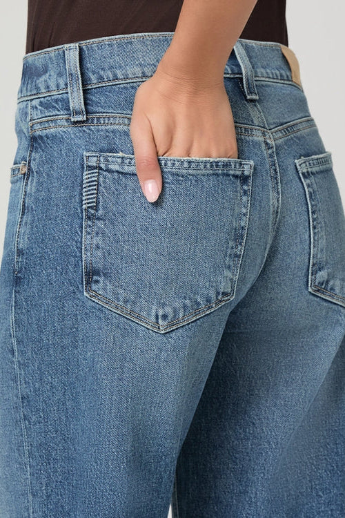 Low-rise straight leg blue jeans with five-pocket styling and visible stitching detail on back pocket.