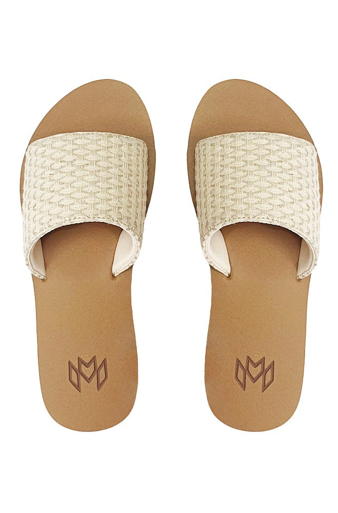 The Malvados Ellie 2- Hampton features tan slide sandals with textured cream woven straps and a geometric logo on the memory foam footbed, shown from above against a white background.