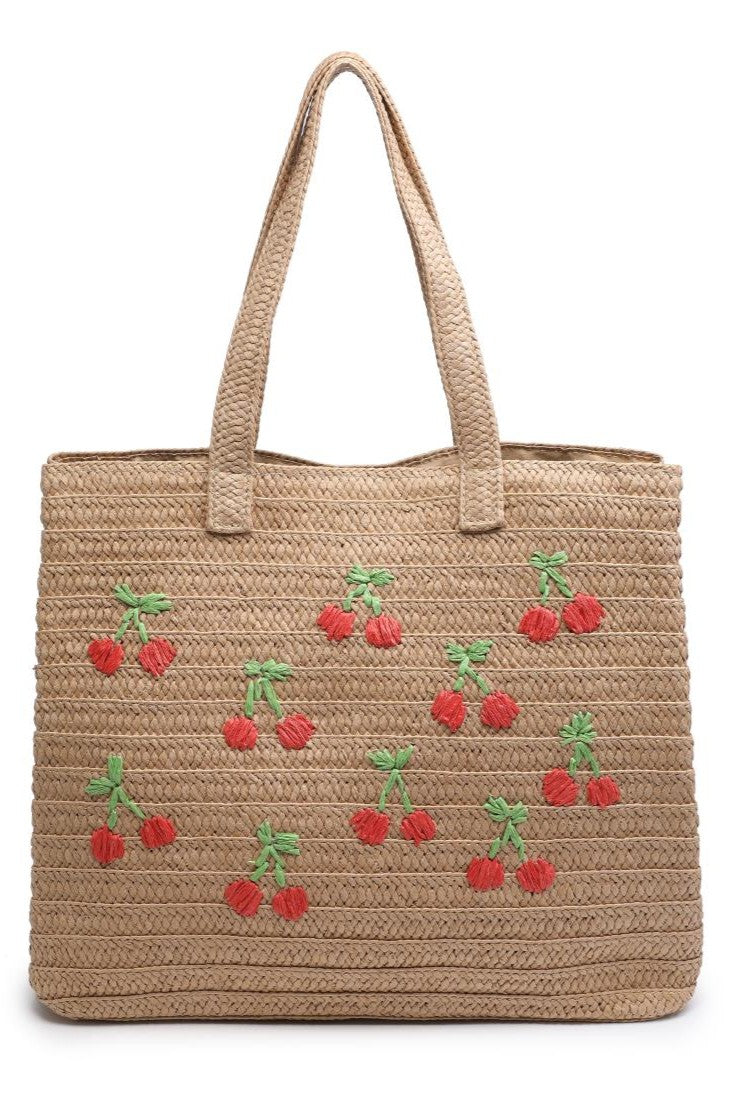 The Urban Expressions Natural Cherry Beach Tote is a woven straw bag with two handles, featuring cherry embroidery with red cherries and green leaves scattered on the front.