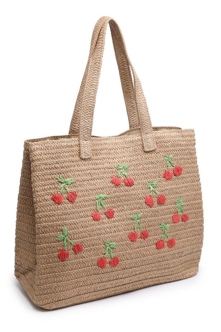 The Urban Expressions Natural Cherry Beach Tote is a woven tan straw bag with two handles, decorated with playful red cherry embroidery and green stems on the front—perfect for your next beach outing.