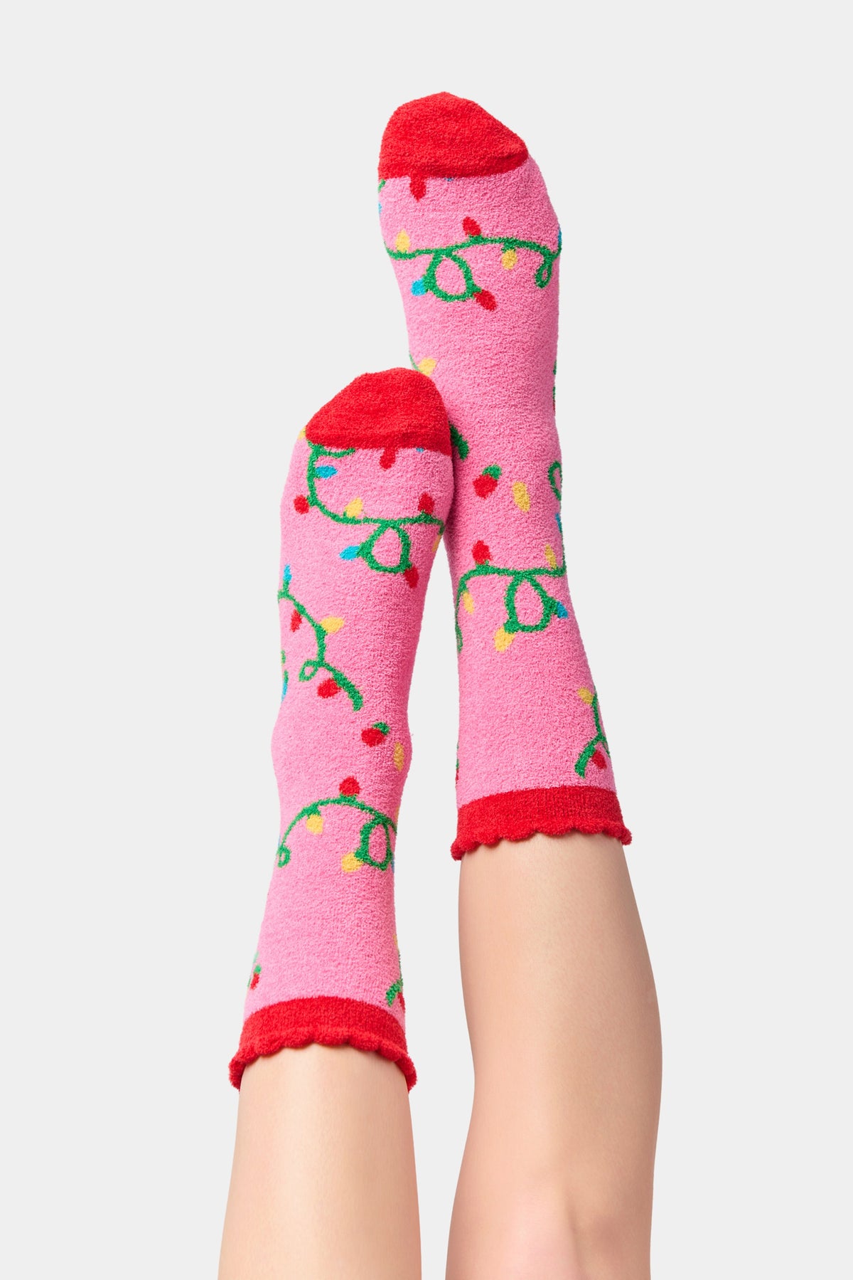 Pink crew socks with red cuffs and green string light patterns with red and yellow bulbs.