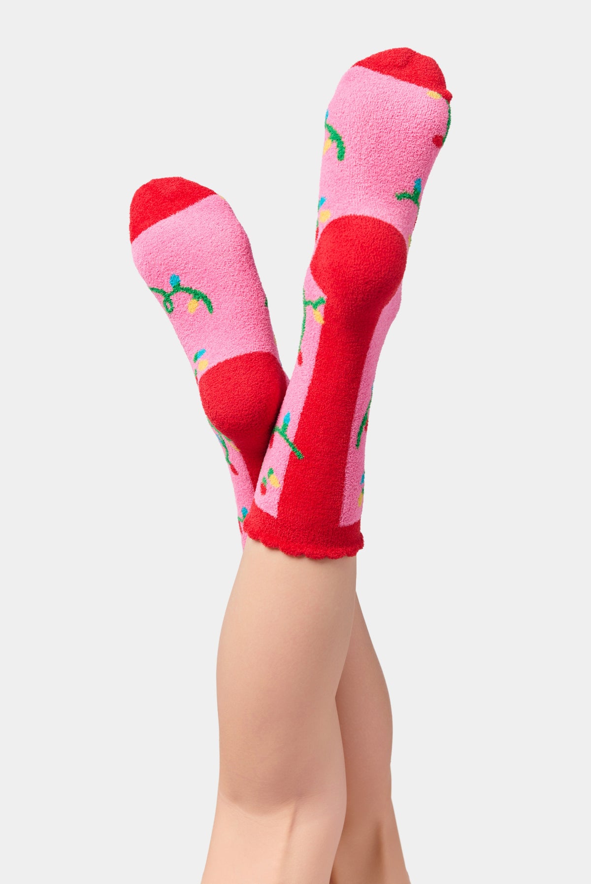 Pink socks with red toe and heel sections, decorated with colorful string light bulb patterns.