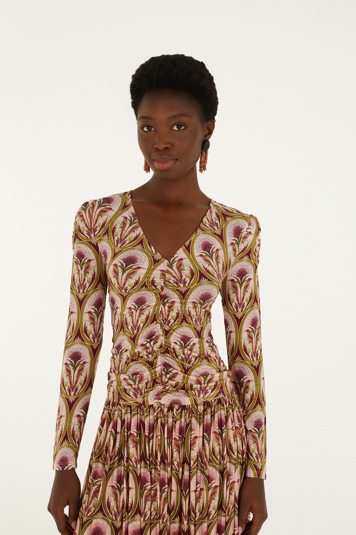 Long sleeve blouse with multicolor floral print in pink, gold, and burgundy tones and V-neckline.