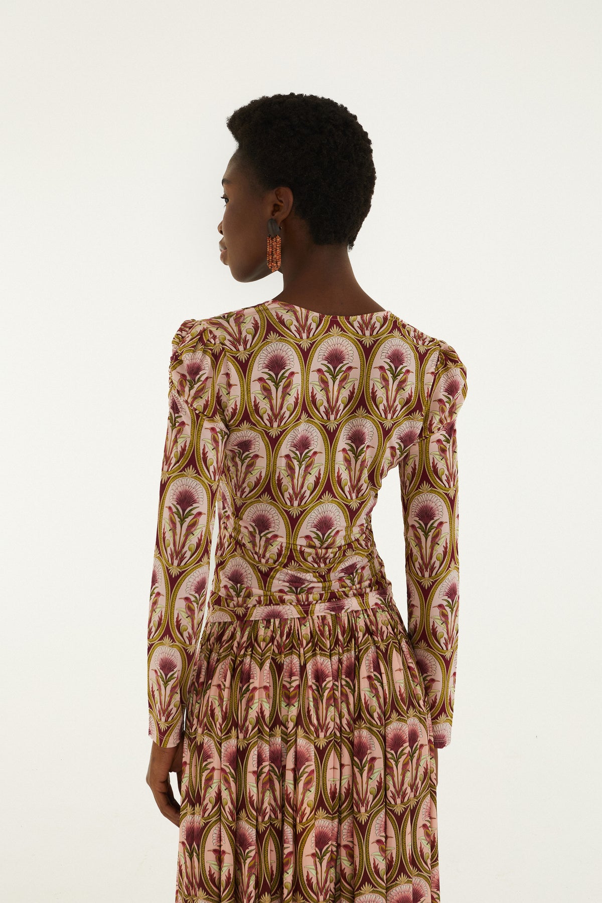 Multicolor long-sleeve blouse with floral print in burgundy, gold, and cream featuring repeating botanical motifs.