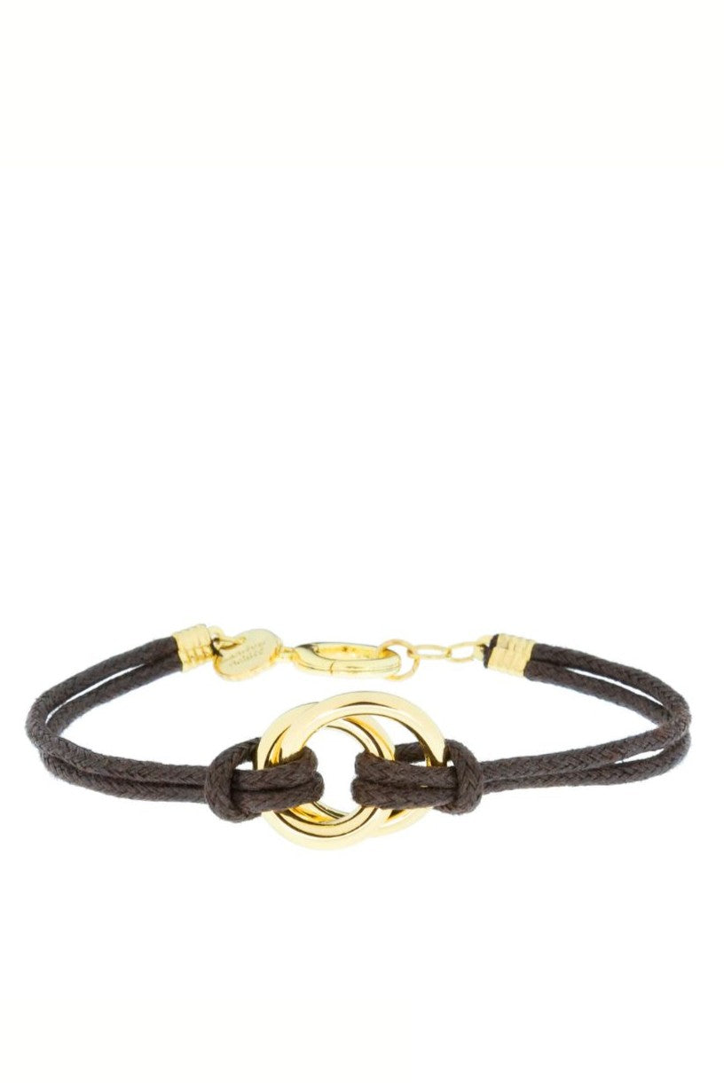 The Marlyn Schiff Oakley Cord Bracelet features a dark brown suede cord, polished gold ring centerpiece, small gold tag, and a gold clasp closure.