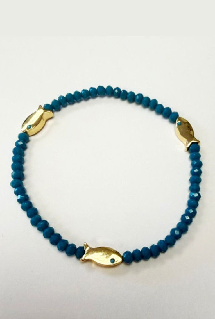 The Marlyn Schiff Fish Bead Bracelet features turquoise beads and three gold fish-shaped charms, evenly spaced for balance, shown on a plain white background.
