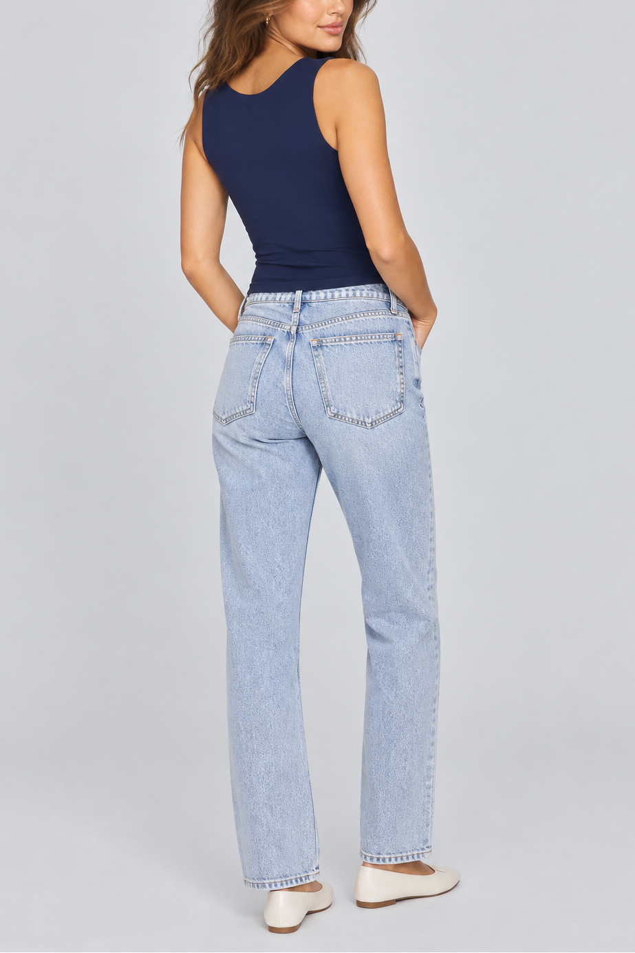 Woman wearing navy sleeveless muscle cami and light blue jeans, shown from behind.