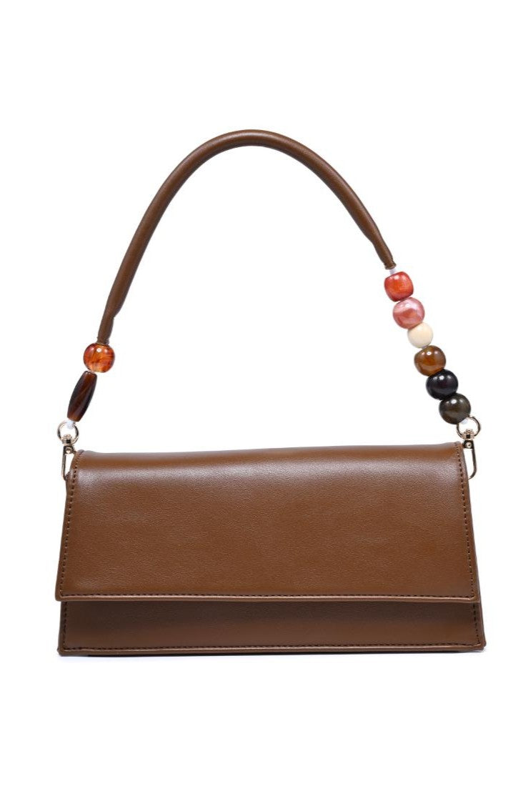 The Brooks Shoulder Bag by Urban Expressions is a brown vegan leather bag with a rectangular flap, a short padded top handle, and multicolored round beads on one side.