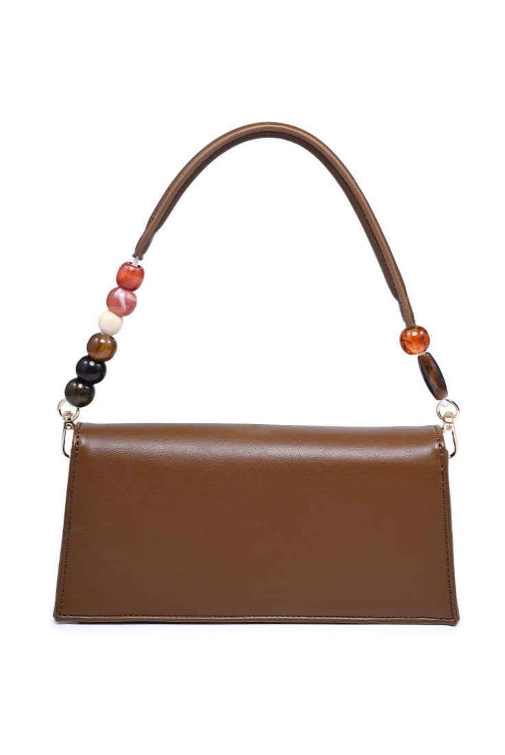 The Brooks Shoulder Bag by Urban Expressions is a rectangular brown vegan leather bag with a padded top handle adorned with colorful beads, gold-tone hardware, and a minimalist design.