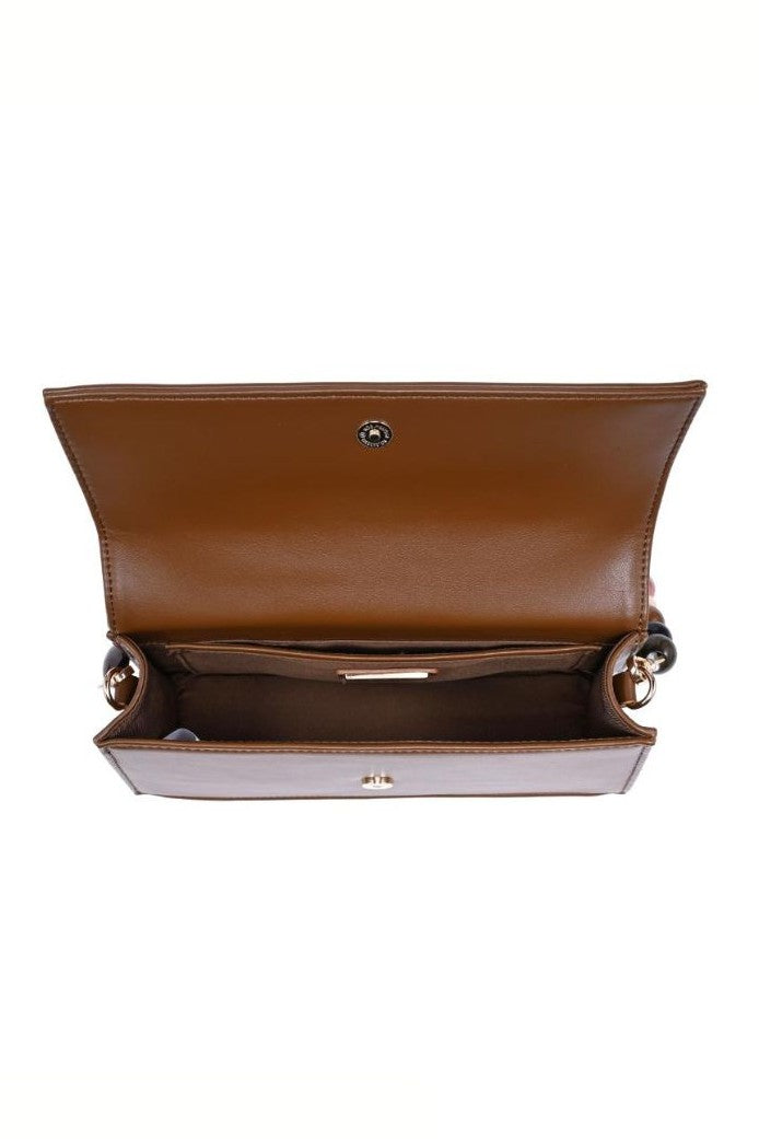 The Urban Expressions Brooks Shoulder Bag in brown vegan leather is shown open with the flap lifted, revealing a spacious main compartment, small pocket, and gold-tone hardware on the sides.