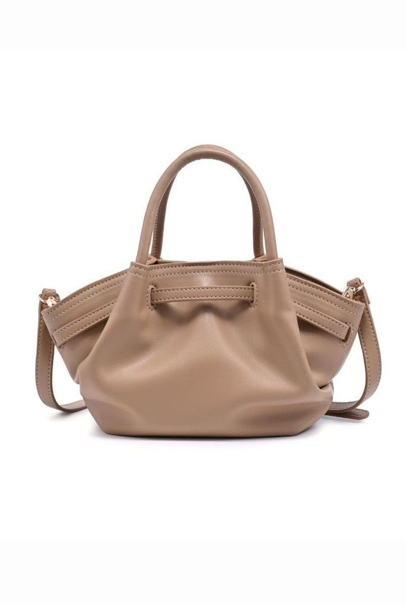 The Urban Expressions Selena Mini Crossbody is a small, tan handbag with short handles, an adjustable detachable shoulder strap, and a soft, minimal design. Its slightly slouchy silhouette is displayed against a white background.