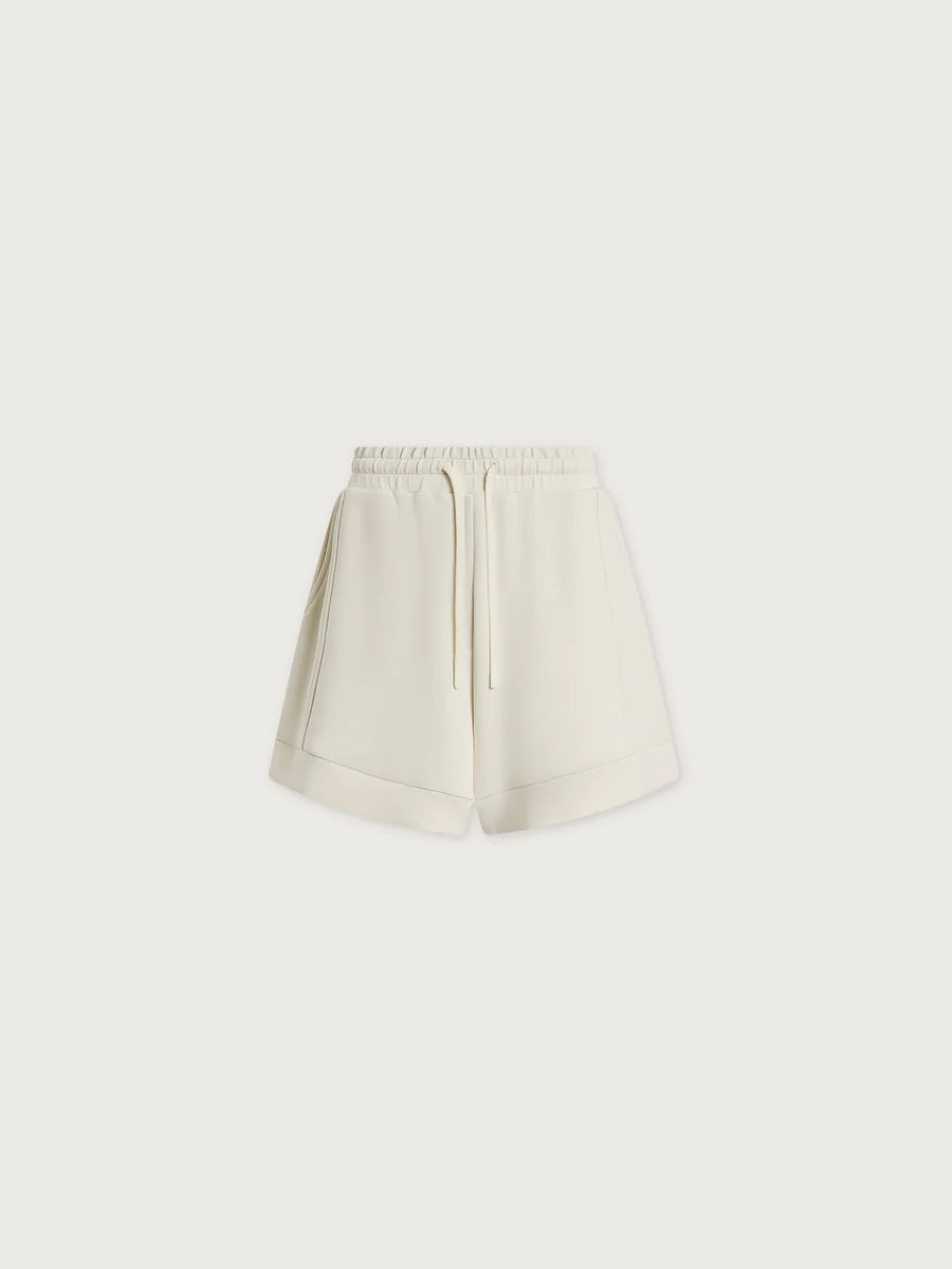The Varley Atrium High Rise Short 4.5 features an off-white A-line design with an elastic waistband, drawstring tie, side pockets, and a relaxed fit—ideal for spring and summer, shown on a plain white background.
