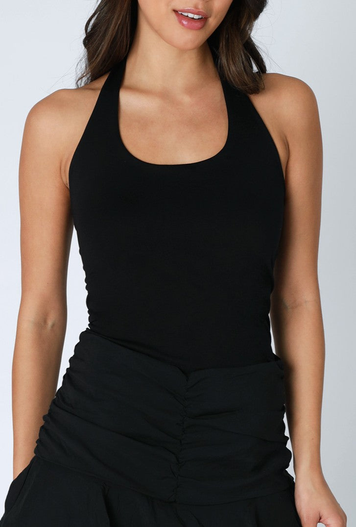 A woman wears the Niki Biki Smooth Halter with a high-waisted, ruched black skirt. The image, cropped from shoulders to thighs, emphasizes the versatile layering of these chic essentials against a neutral background.