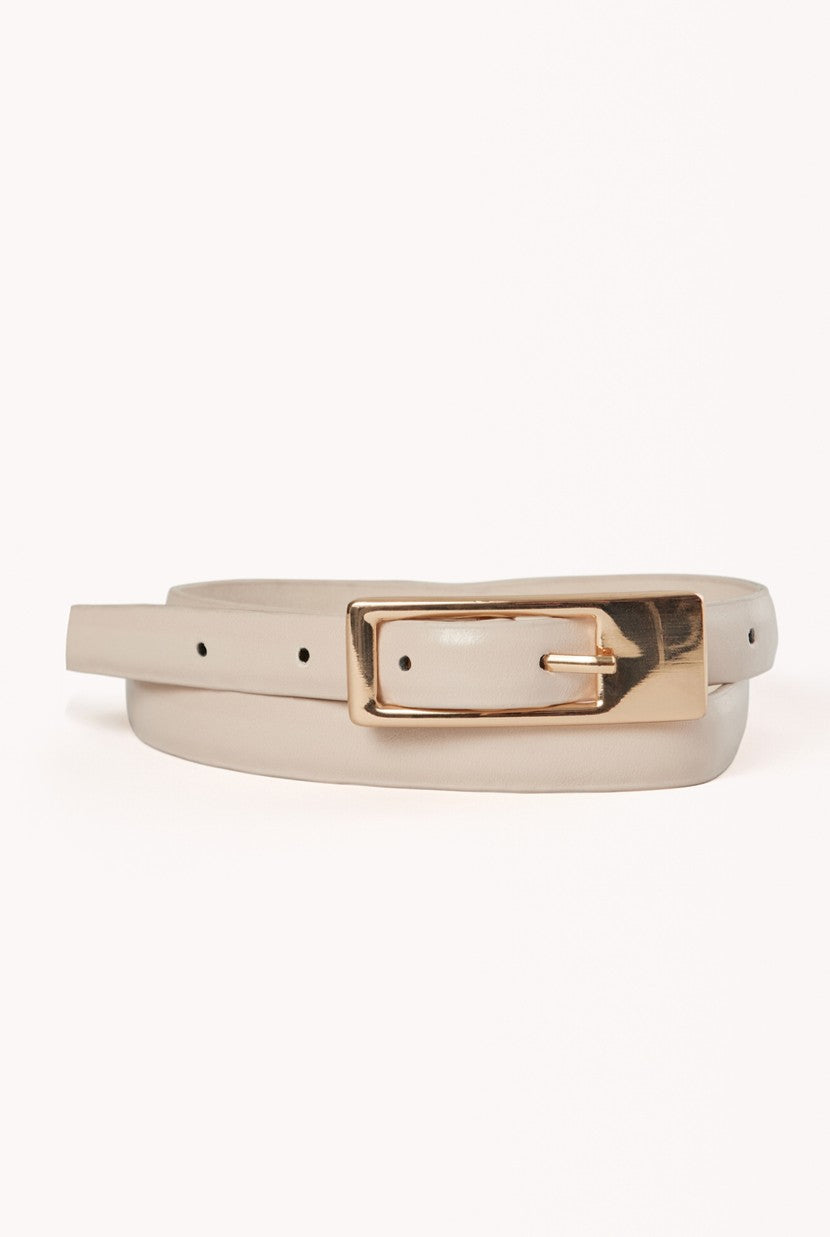 The Billini Gloria Thin Belt in beige features a minimalist design with a shiny gold rectangular buckle, shown coiled on a white background.