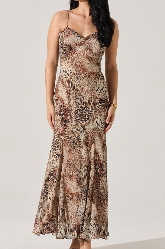 A woman wears the Maeryn Maxi Dress by ASTR, a sleeveless, ankle-length dress with thin straps and a brown, beige, and black animal print. Fitted at the top and flared at the bottom, it offers effortless elegance with its flowing silhouette.
