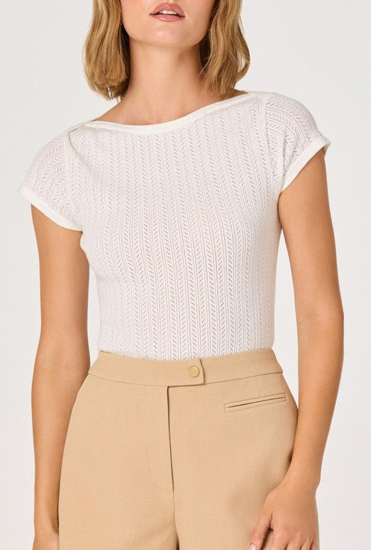 A woman models the ASTR River Short Sleeve Top—a white, slim-fit, open-knit eyelet tee—paired with high-waisted beige trousers. The image is cropped above her chin and thighs on a plain background.