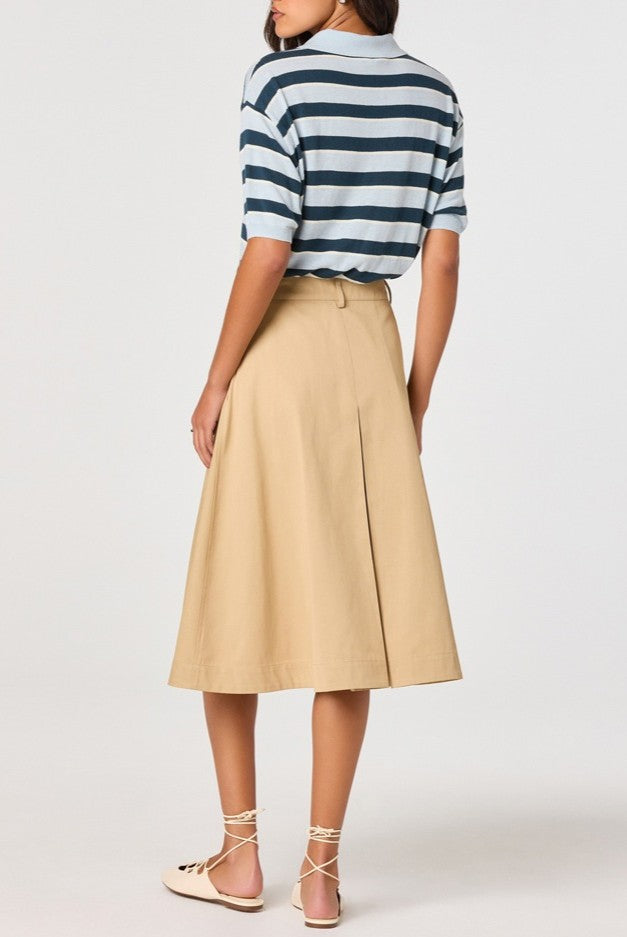 A person wearing the ASTR Scottie Sweater, a relaxed fit polo featuring blue and white stripes, is paired with a beige midi skirt and cream lace-up flats, standing with their back to the camera against a plain background.