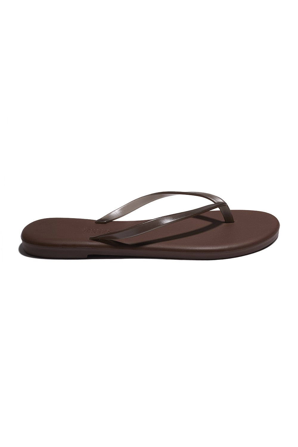 The Tkees Aqua Tkees In Brun sandal features a thin, glossy brown strap, cushioned footbed, and flat sole, shown against a white background.
