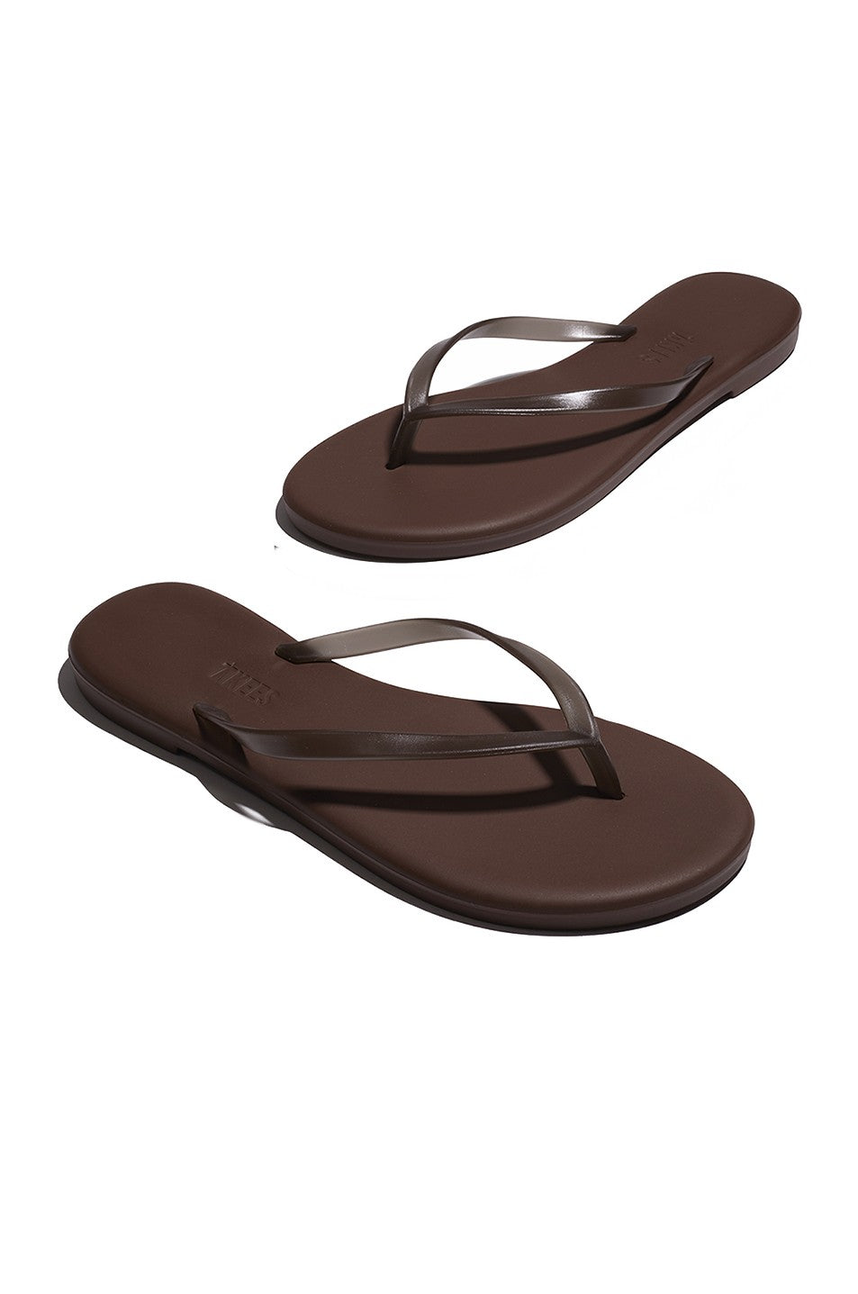 Aqua Tkees In Brun by Tkees: brown flip-flop sandals featuring thin straps and a cushioned footbed, shown on a white background.