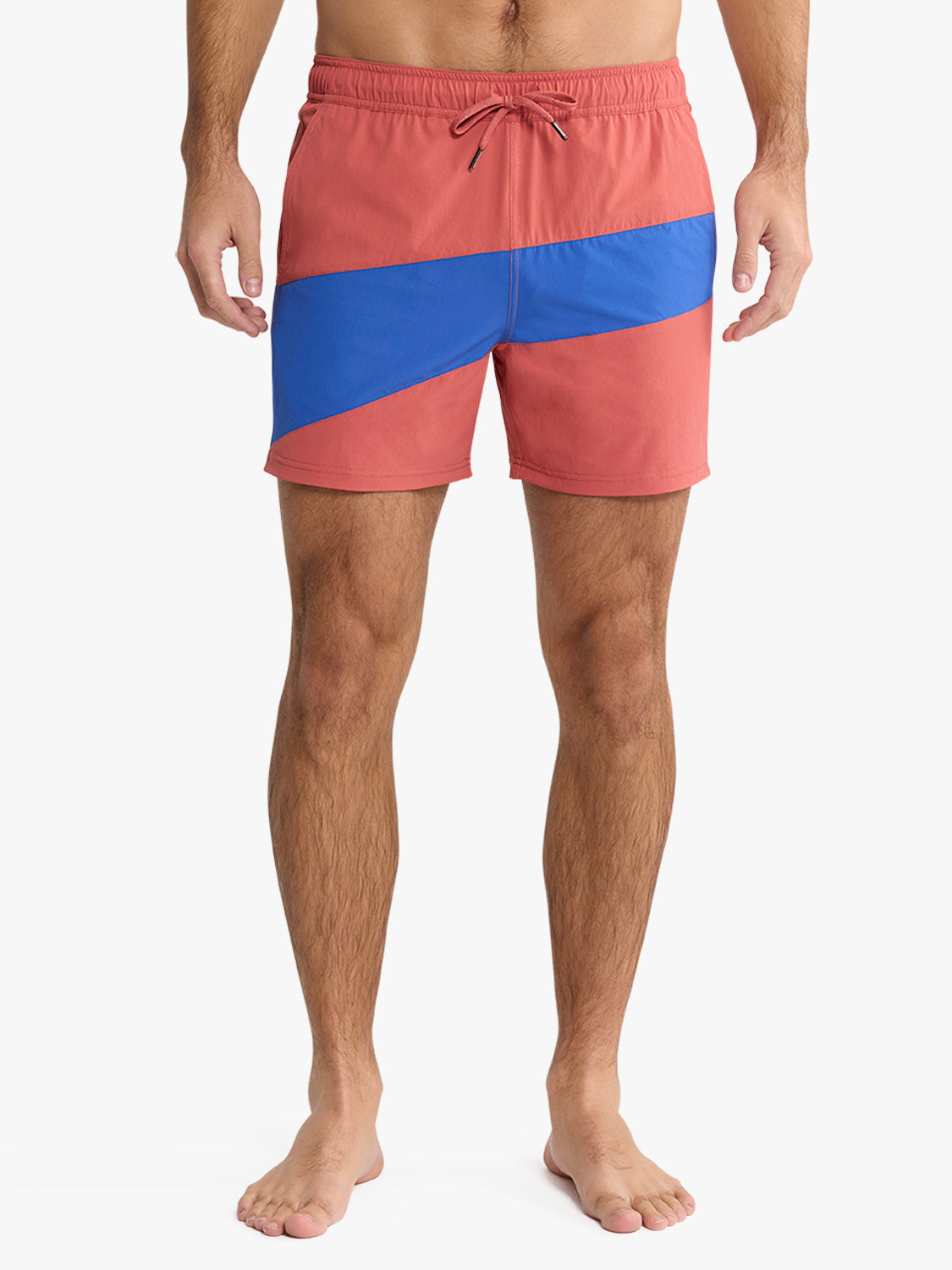 A person wearing Fair Harbor's Bungalow Trunk 5 In Nautical Colorblock swim trunks is shown barefoot against a white background, with only the lower torso and legs visible.