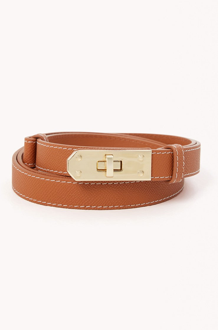 The Blake Belt by Billini is a tan leather adjustable belt with white stitching, featuring sleek gold hardware and a turn-lock closure, shown coiled on a white background.