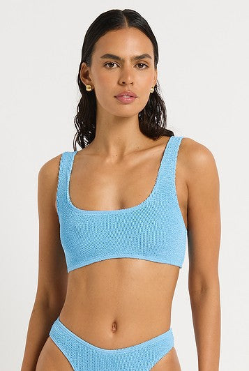 A woman models the Bond-Eye Cloud Blue Malibu 2.0 Crop, a textured bikini with full bust support, scoop neck top, and high-cut bottoms, set against a plain white background.