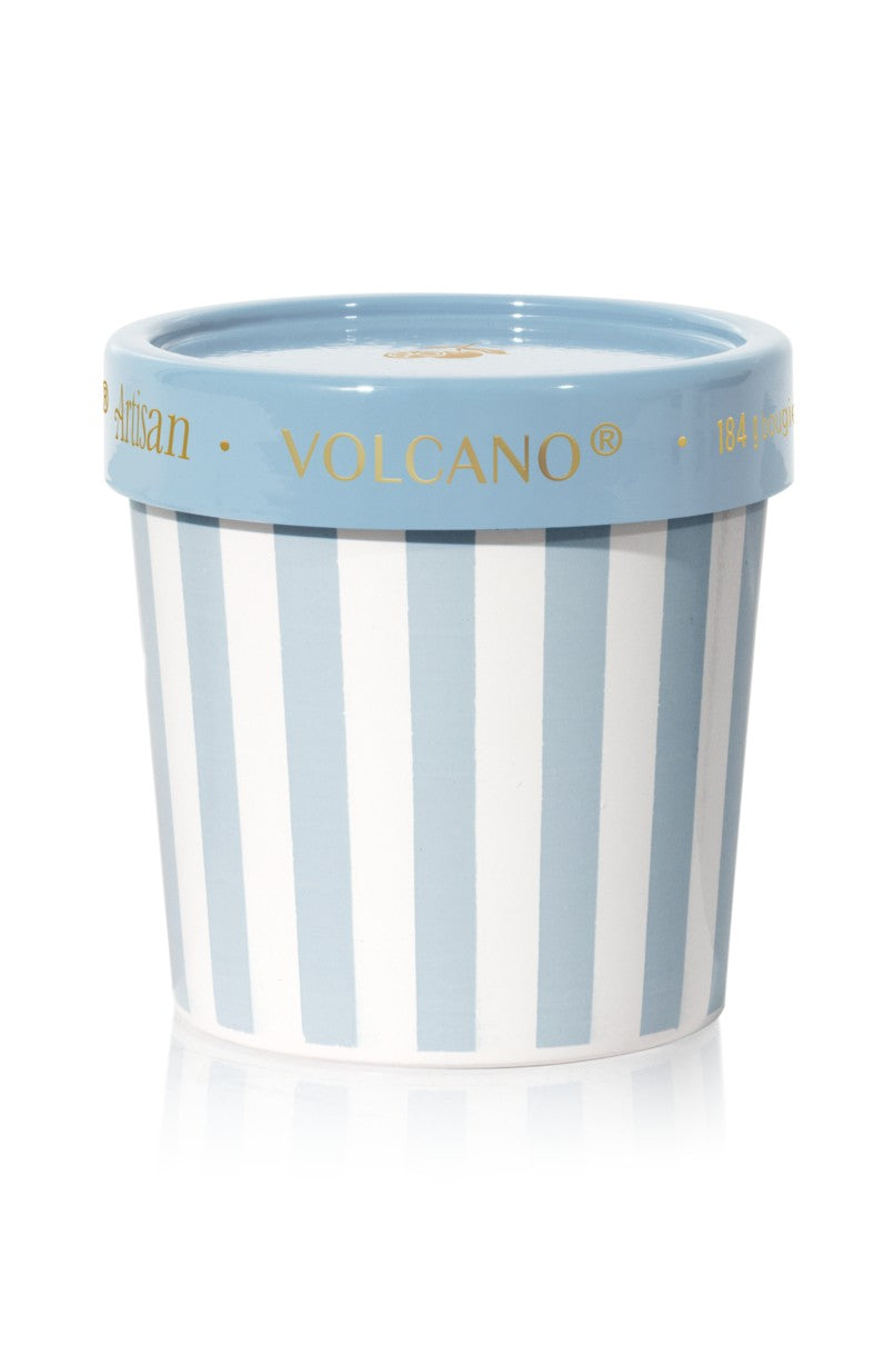 The Vacation Volcano Gelato Cup Candle features a blue multi-striped design with a matching blue lid. Gold text, including “VOLCANO,” accents the rim, capturing the fresh Capri fragrance of sugared citrus within.