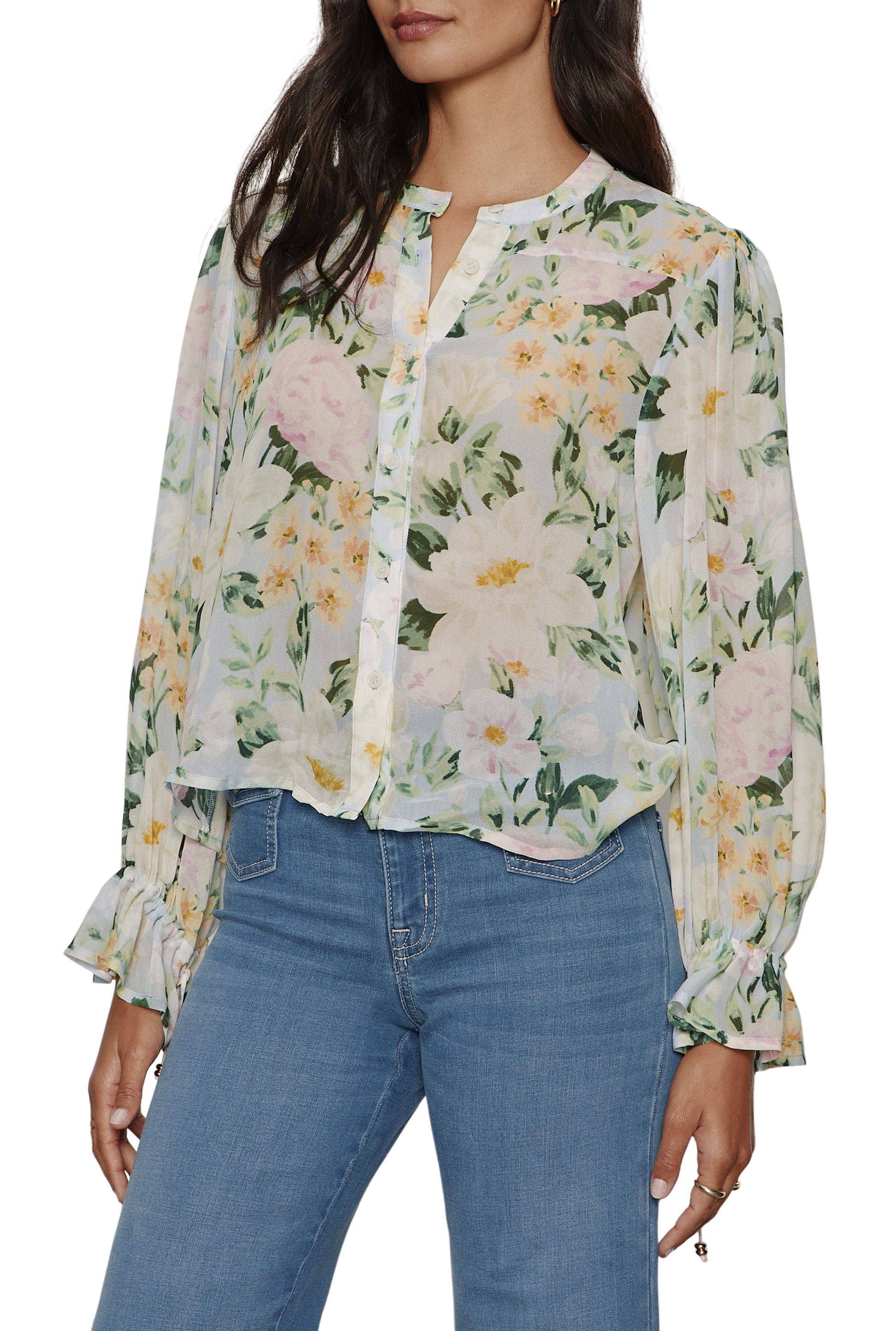 A woman wears the Sanctuary Femme Muse Button Blouse, a light, sheer long-sleeve top with pastel floral print and tie cuffs, buttoned at the front and styled with blue high-waisted jeans. Her hair is down; her face partially out of frame.