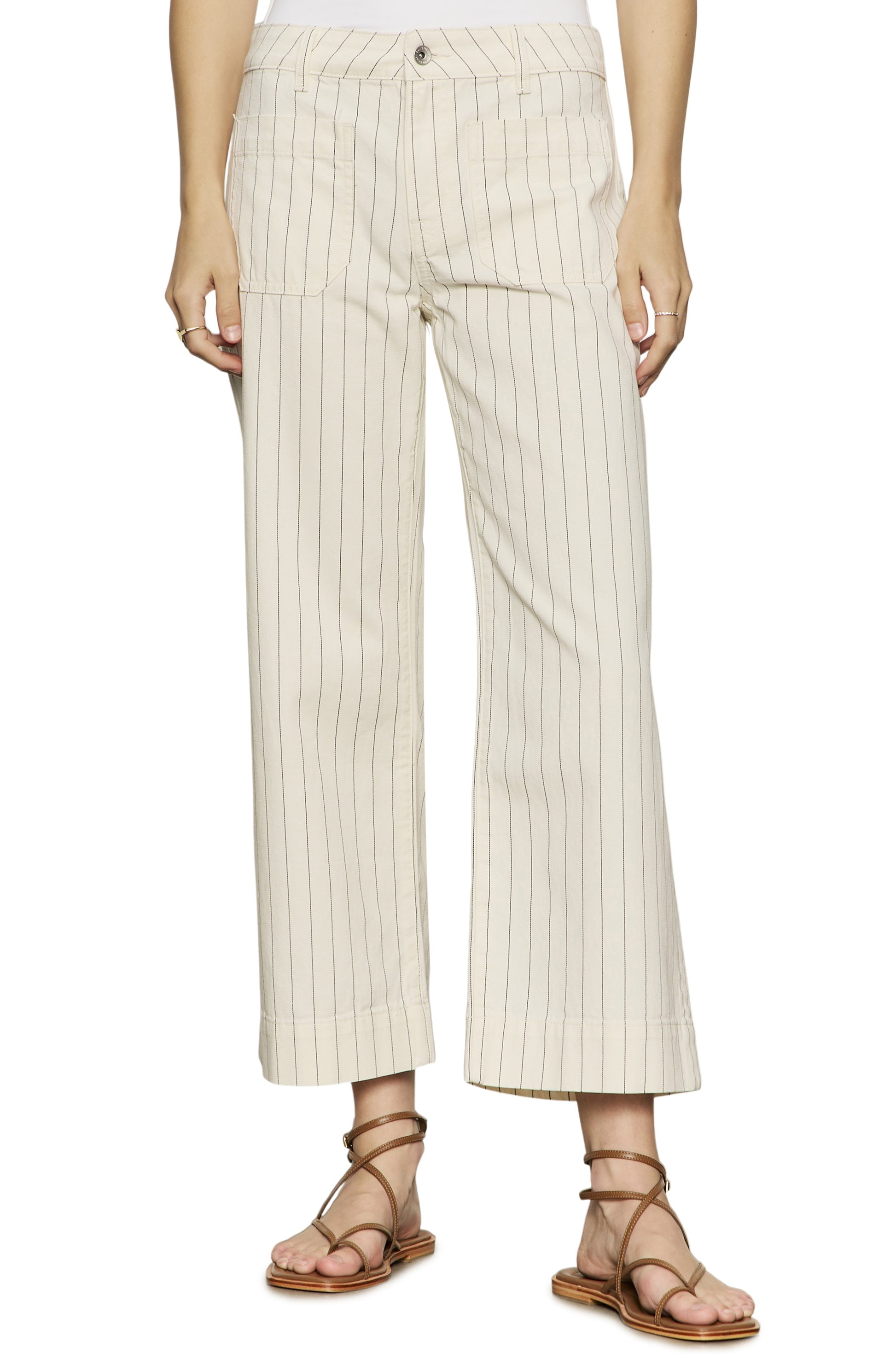 A person wearing Sanctuary's The Marine Bleached White Pinstripe cropped wide leg pants with thin black stripes and a relaxed fit, paired with brown strappy flat sandals. The upper body is mostly out of frame.
