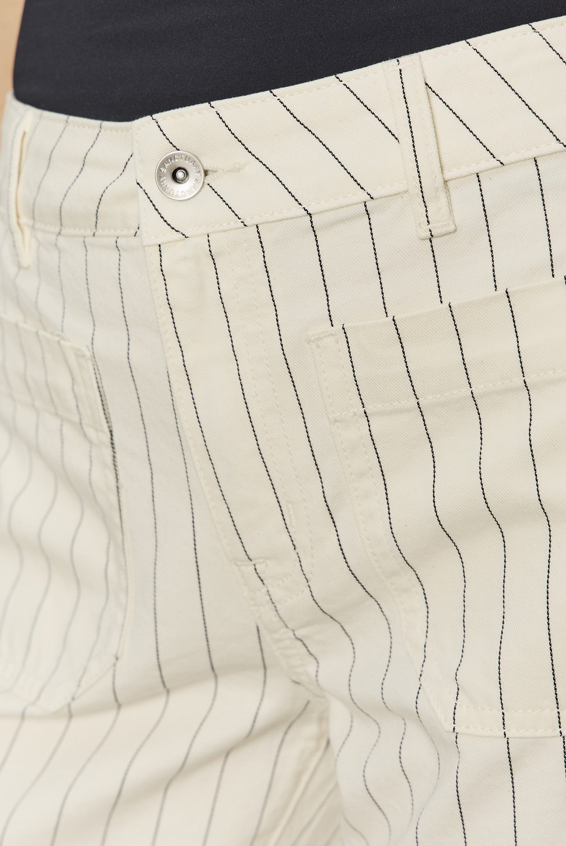 Close-up of Sanctuary’s The Marine Bleached White Pinstripe pants featuring thin black pinstripes, a silver button, and a relaxed fit.