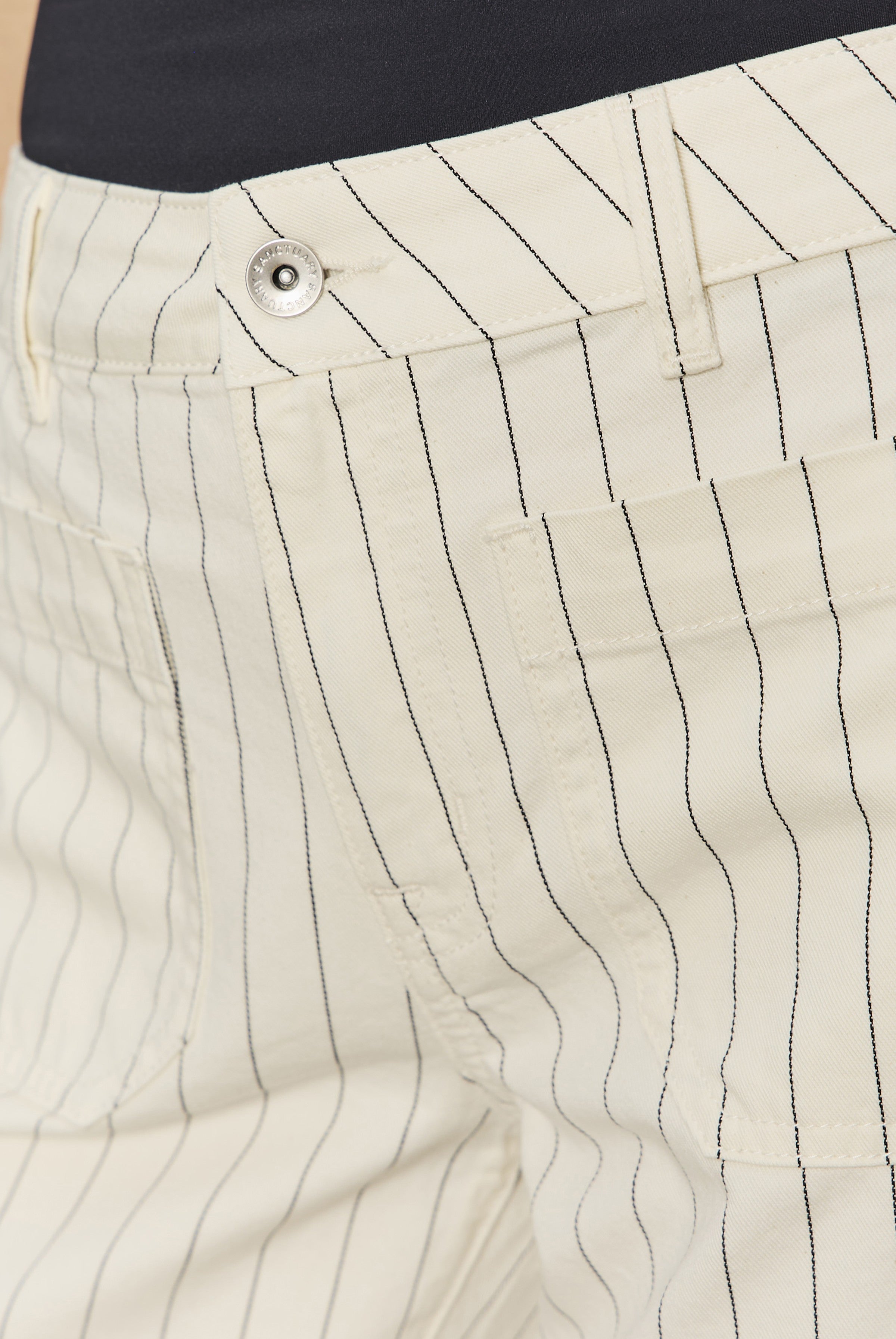 Close-up of Sanctuary’s The Marine Bleached White Pinstripe pants featuring thin black pinstripes, a silver button, and a relaxed fit.