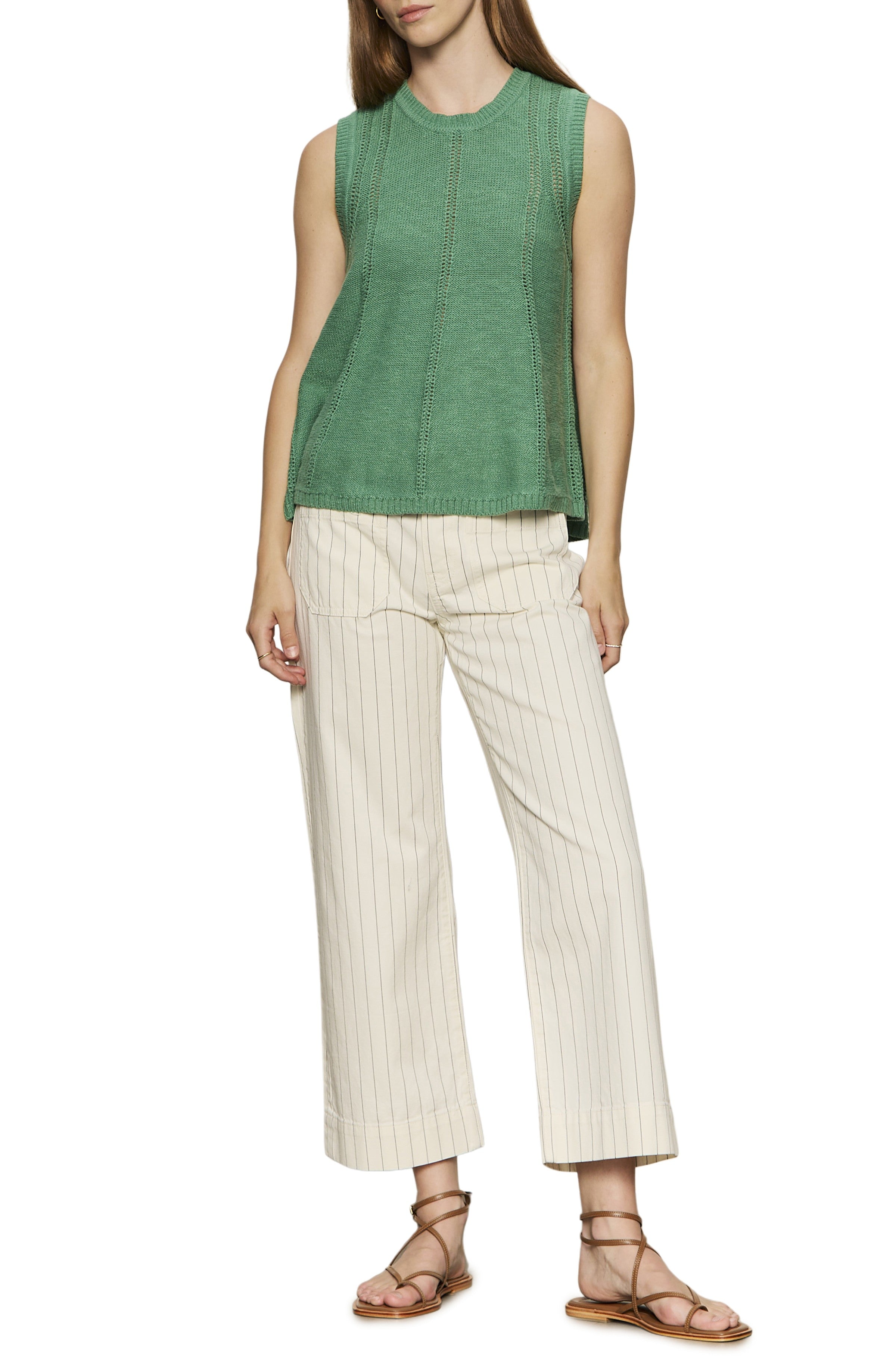 A woman wears Sanctuary's The Marine Bleached White Pinstripe relaxed fit cropped wide leg pants with a sleeveless green knit top and brown strappy sandals, standing against a white background. Her head is partially out of frame.