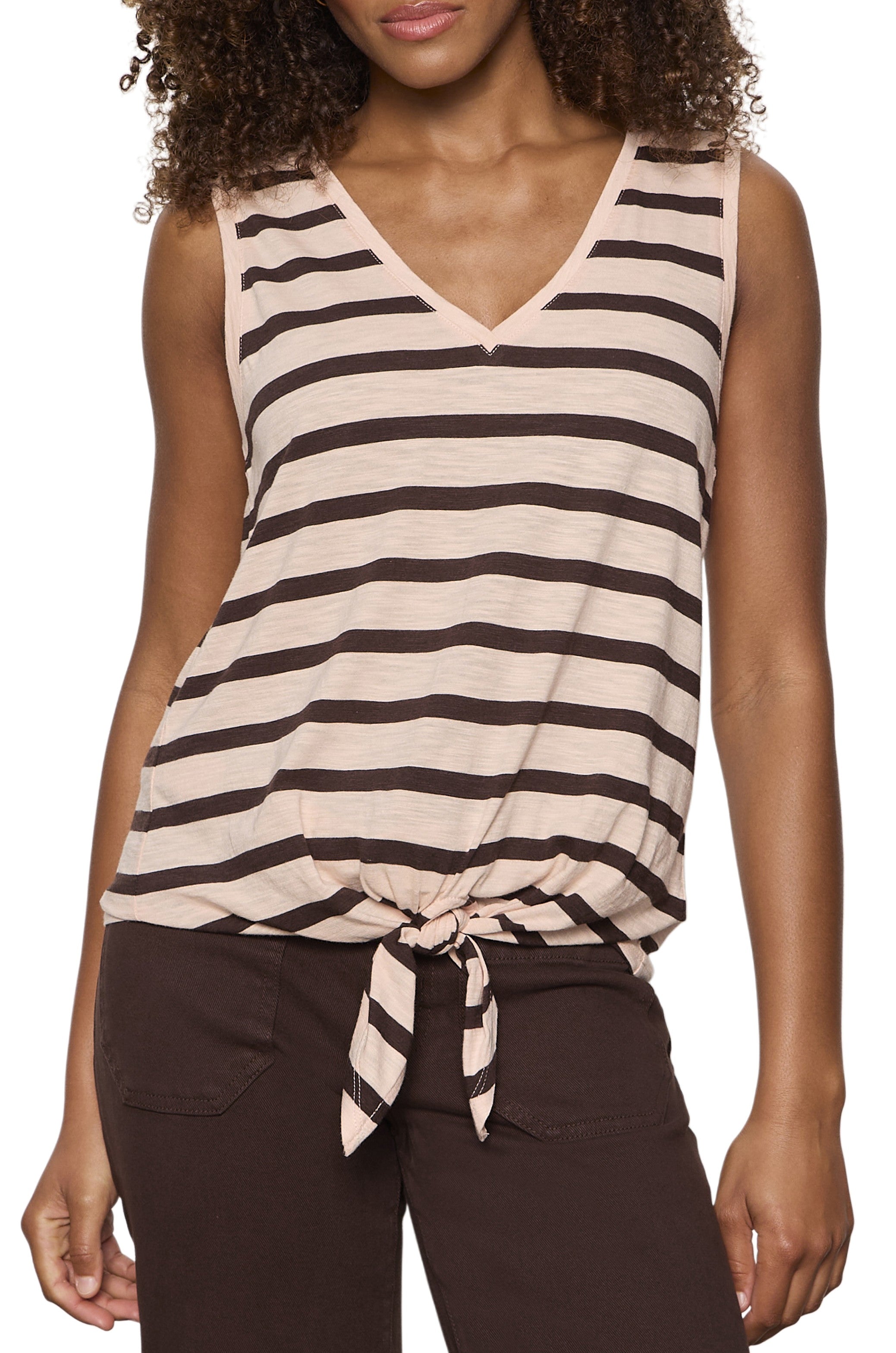 A woman wears the Sanctuary V Neck Tie Tank in Pink Multi, a relaxed fit sleeveless top with a front waist tie, paired with dark brown soft cotton rayon pants.
