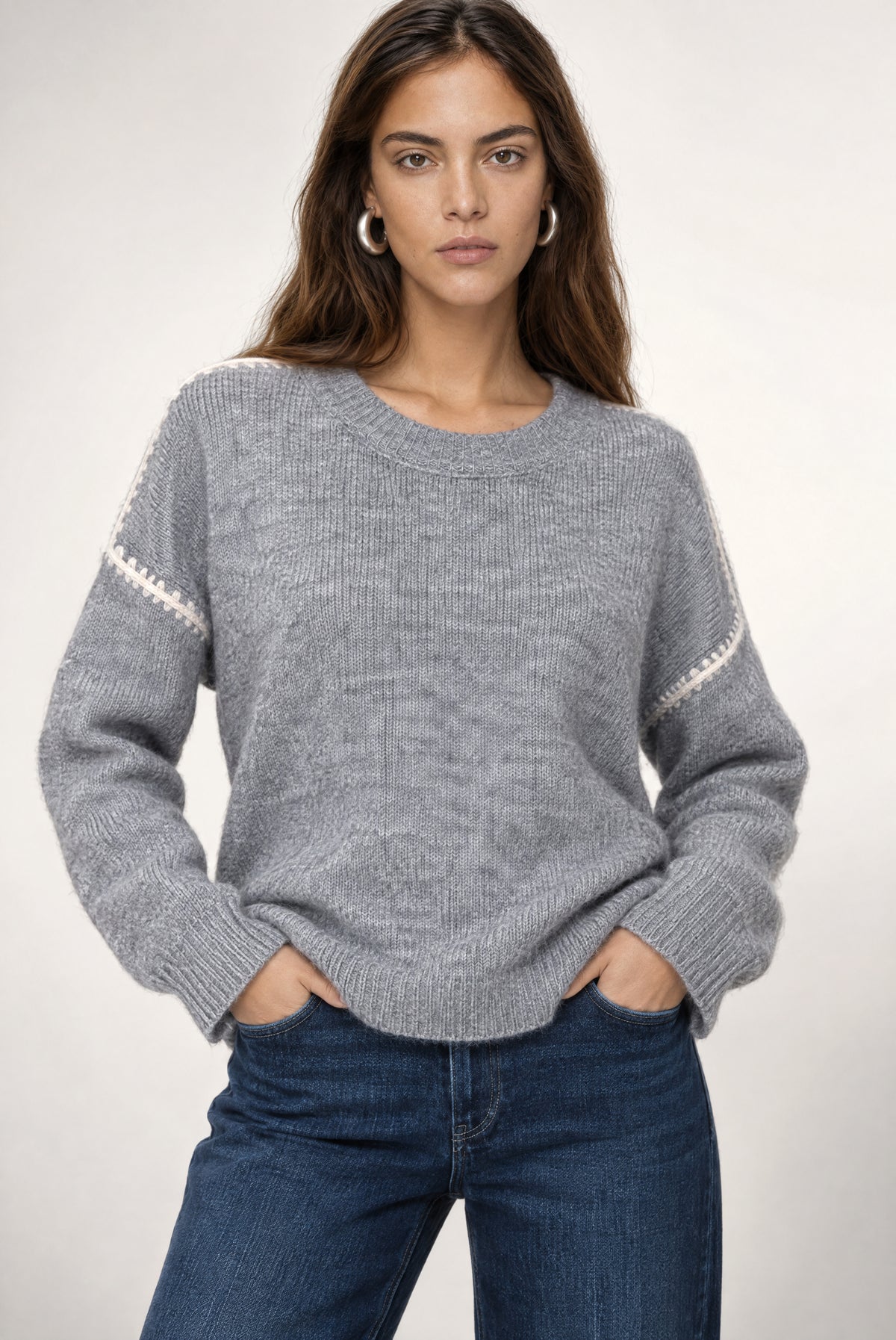 Heather grey ribbed sweater with ivory stripe detail on sleeves, crew neckline, worn with dark jeans.