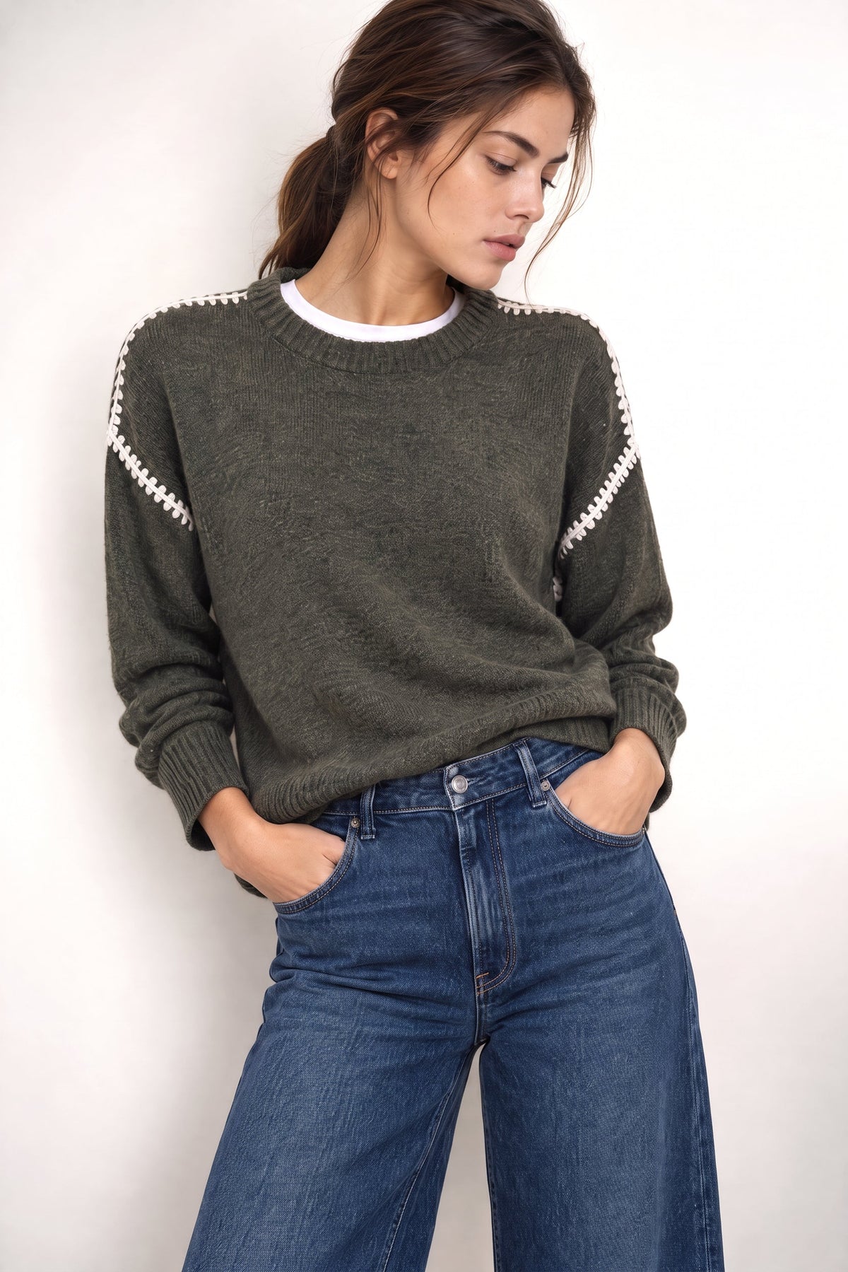 Olive green crewneck sweater with ivory contrast trim on sleeves and white ribbed collar, worn with blue jeans.