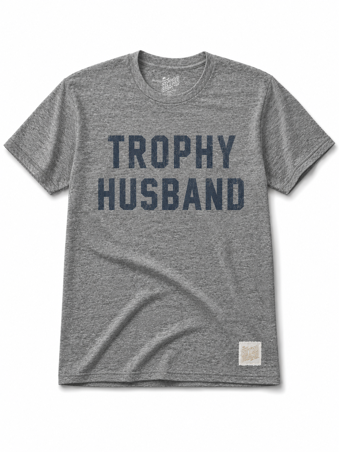 The Trophy Husband tee by Original Retro Brand is a super soft unisex shirt in streaky grey with bold dark blue “TROPHY HUSBAND” lettering on the chest and a small fabric label near the hem.