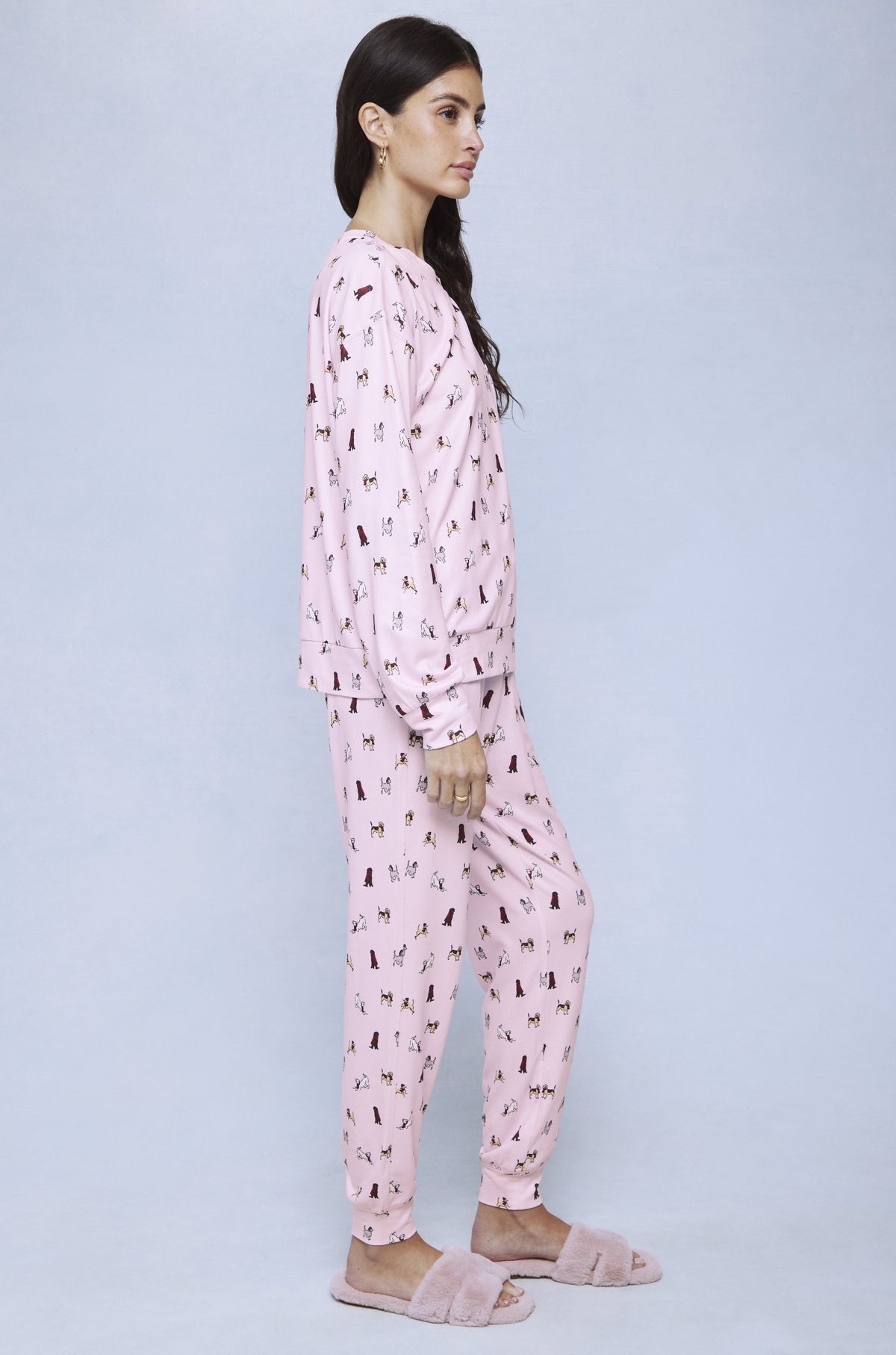 Pink jersey pajama set with small dog print pattern throughout, shown on model from side view.