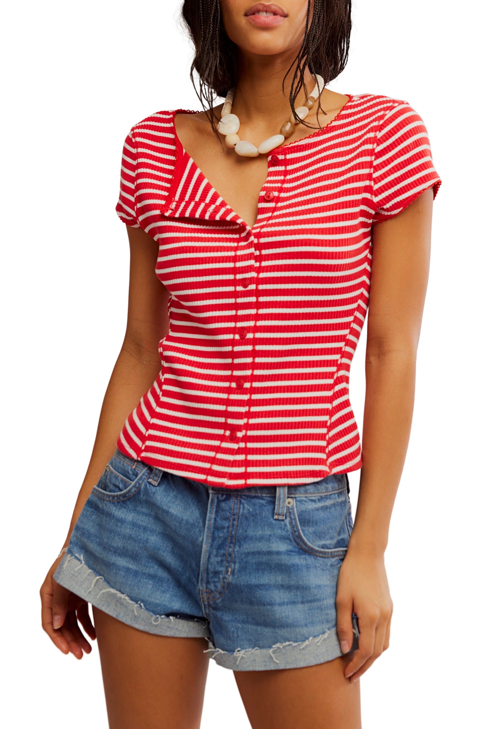 A woman wears the Most Wanted Striped Cardi by Free People in RED/WHITE with blue denim shorts and a chunky white necklace, standing against a white background.