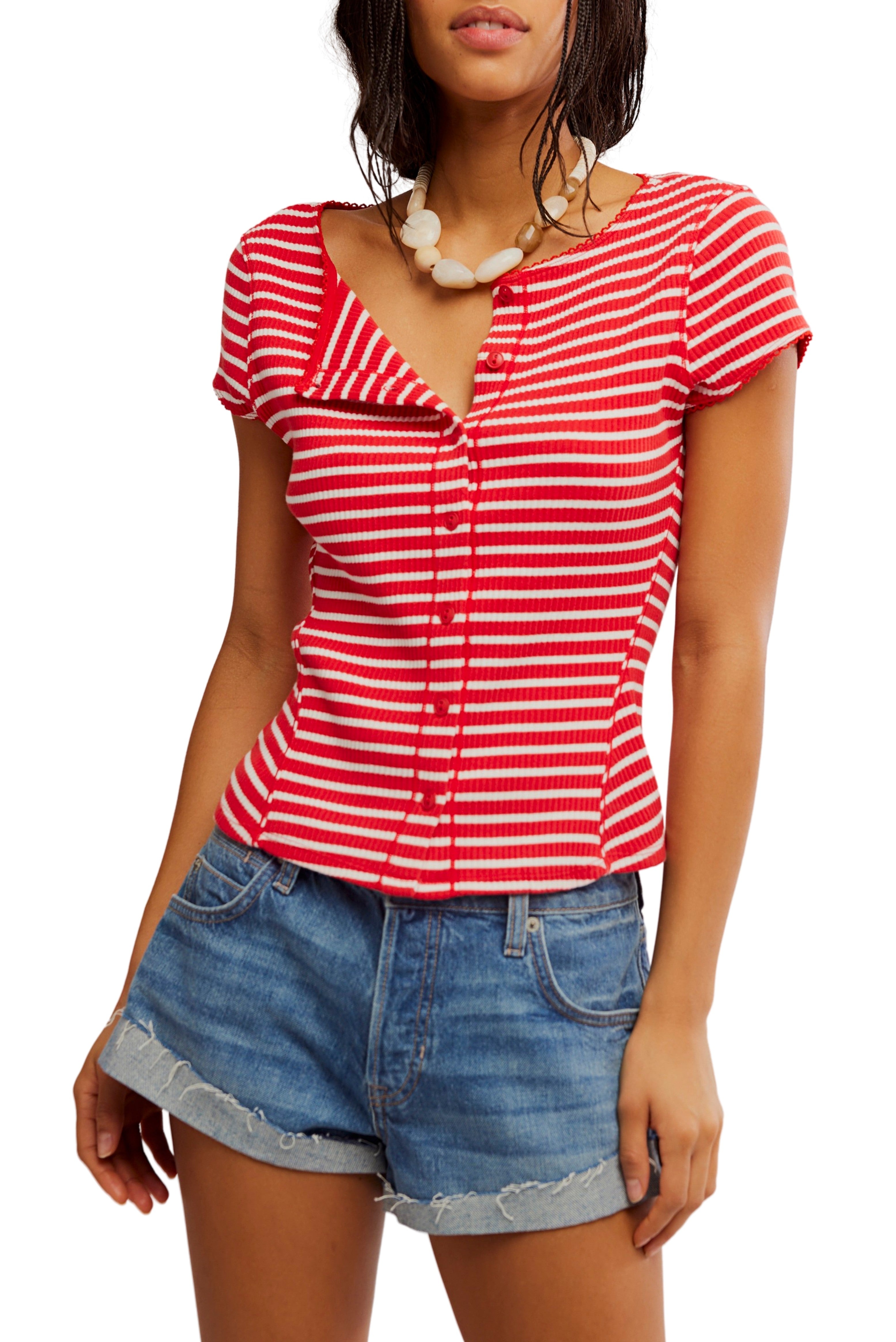 A woman wears the Most Wanted Striped Cardi by Free People in RED/WHITE with blue denim shorts and a chunky white necklace, standing against a white background.
