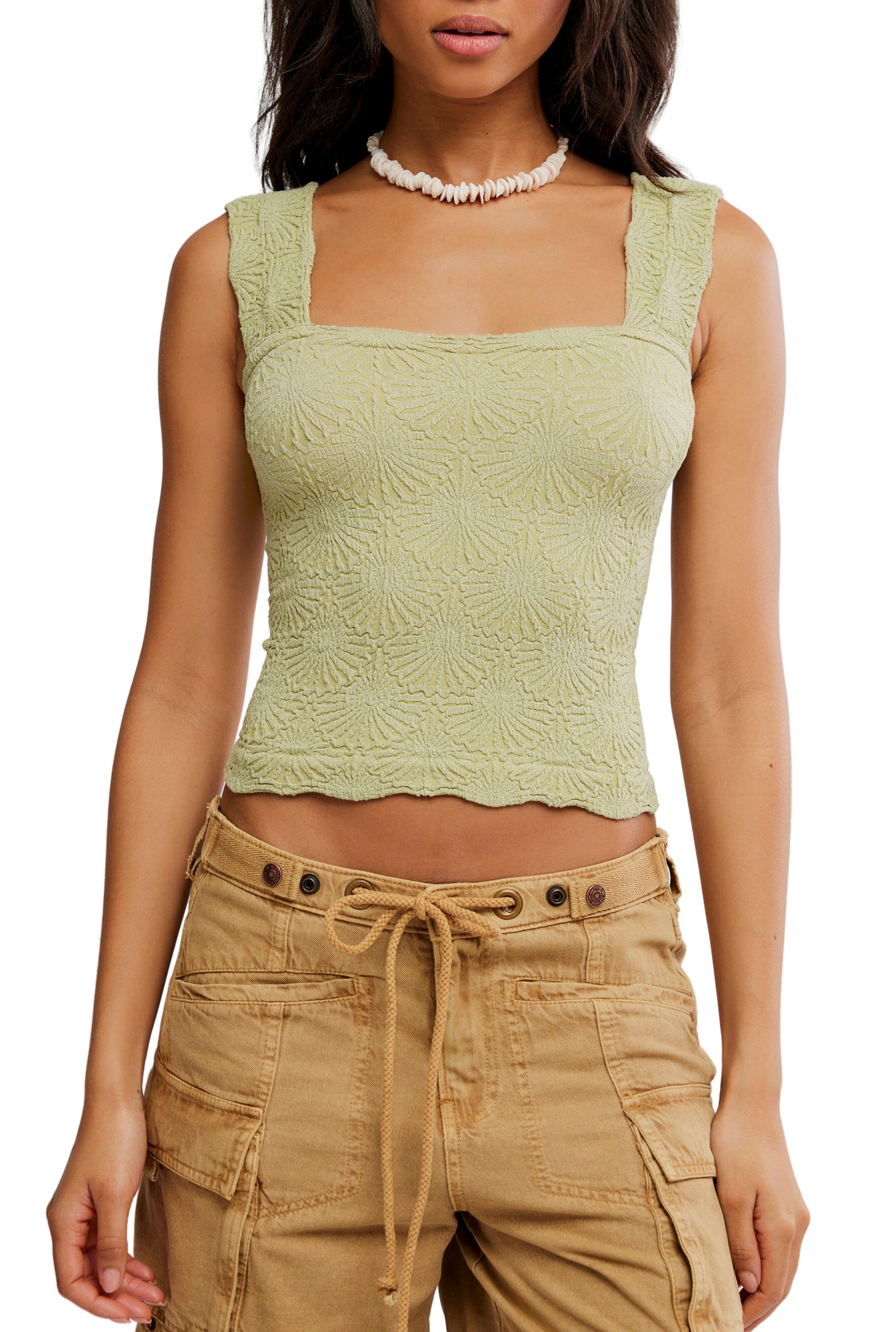 A woman wears the Free People Love Letter Cami in mint green, a textured square-neck cropped top with a subtle jacquard floral design, styled with beige cargo pants and a white shell necklace, shown from shoulders to hips.
