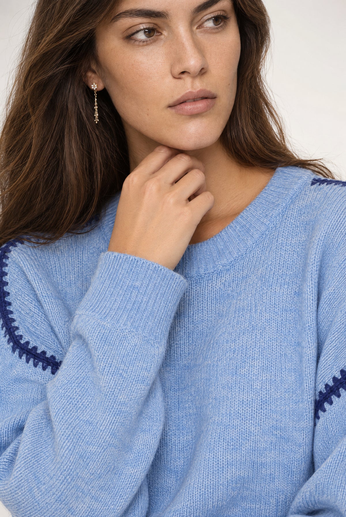 Woman wearing light blue ribbed sweater with navy trim detail on sleeves.