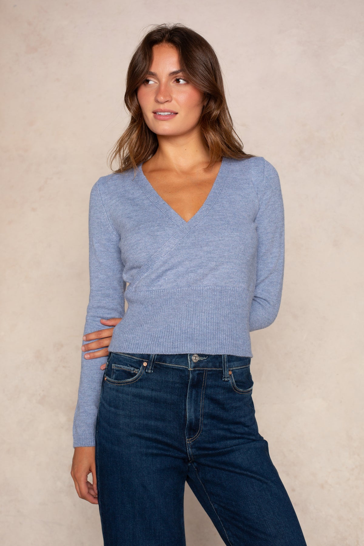 Periwinkle blue ribbed wrap top with surplice neckline and cutout sleeves worn with dark denim jeans.